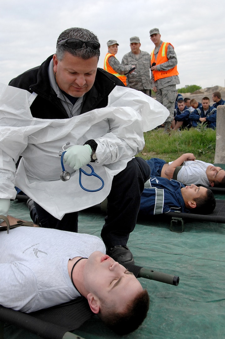 Mr. Domingo Arredondo tends to a patient while exercise evaluation team members look on during an anti-terrorism exercise at Lackland Air Force Base, March 30.  The three-day exercise simulated the release of a nerve agent and involved units at Lackland, Randolph AFB and Ft. Sam Houston, Texas. Mr. Arredondo is a paramedic assigned to the 59th Emergency Medical Squadron at Lackland. (U.S. Air Force Photo/Staff Sgt. Josie Walck)