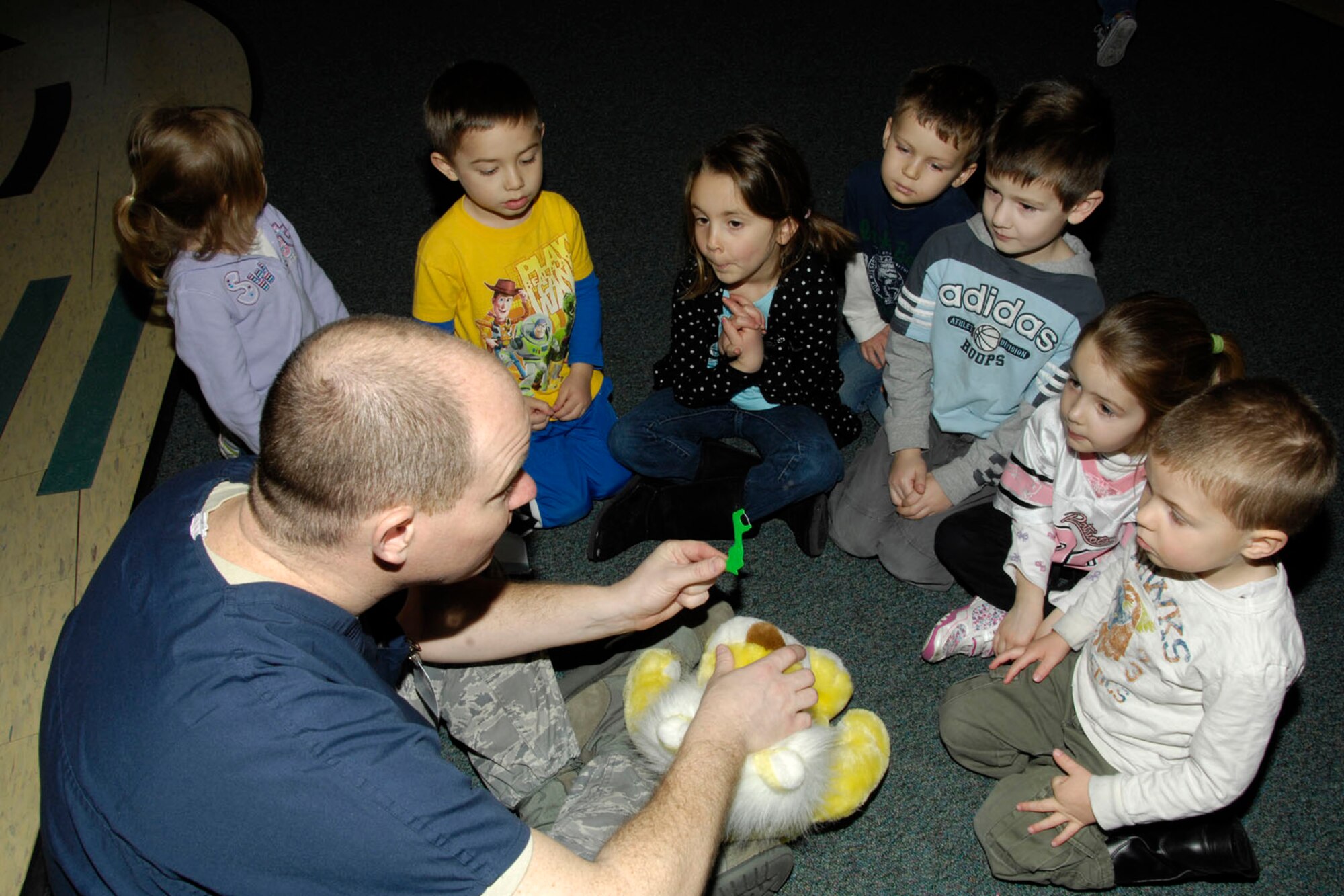 HANSCOM AIR FORCE BASE, Mass. – Master Sgt. Rich Thorpe, from the 66th Medical Squadron’s Dental Flight, demonstrates how to floss using a stuffed animal prop to children at the Child Development Center March 25. Dental Flight members visited the CDC to teach kids about good dental hygiene. (U.S. Air Force photo by Linda LaBonte Britt)