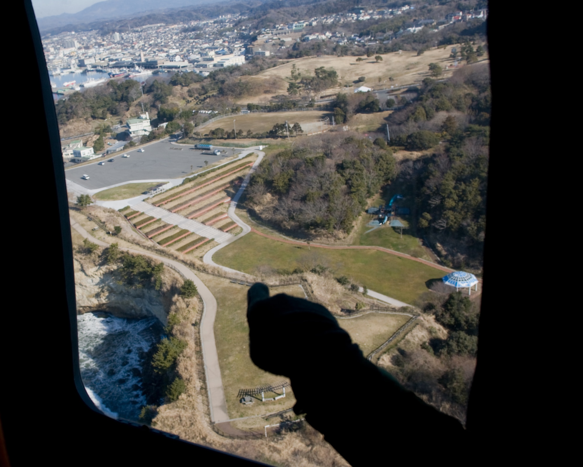 ONAHAMA, Japan -- An HH-60G Pave Hawk flight engineer points to a landing area March 28, 2011 over Onahama, Fukushima Prefecture. The U.S. military is fully committed to supporting the disaster response efforts of the Government of Japan and the Japan Self-Defense Force. (U.S. Air Force photo/Osakabe Yasuo) 