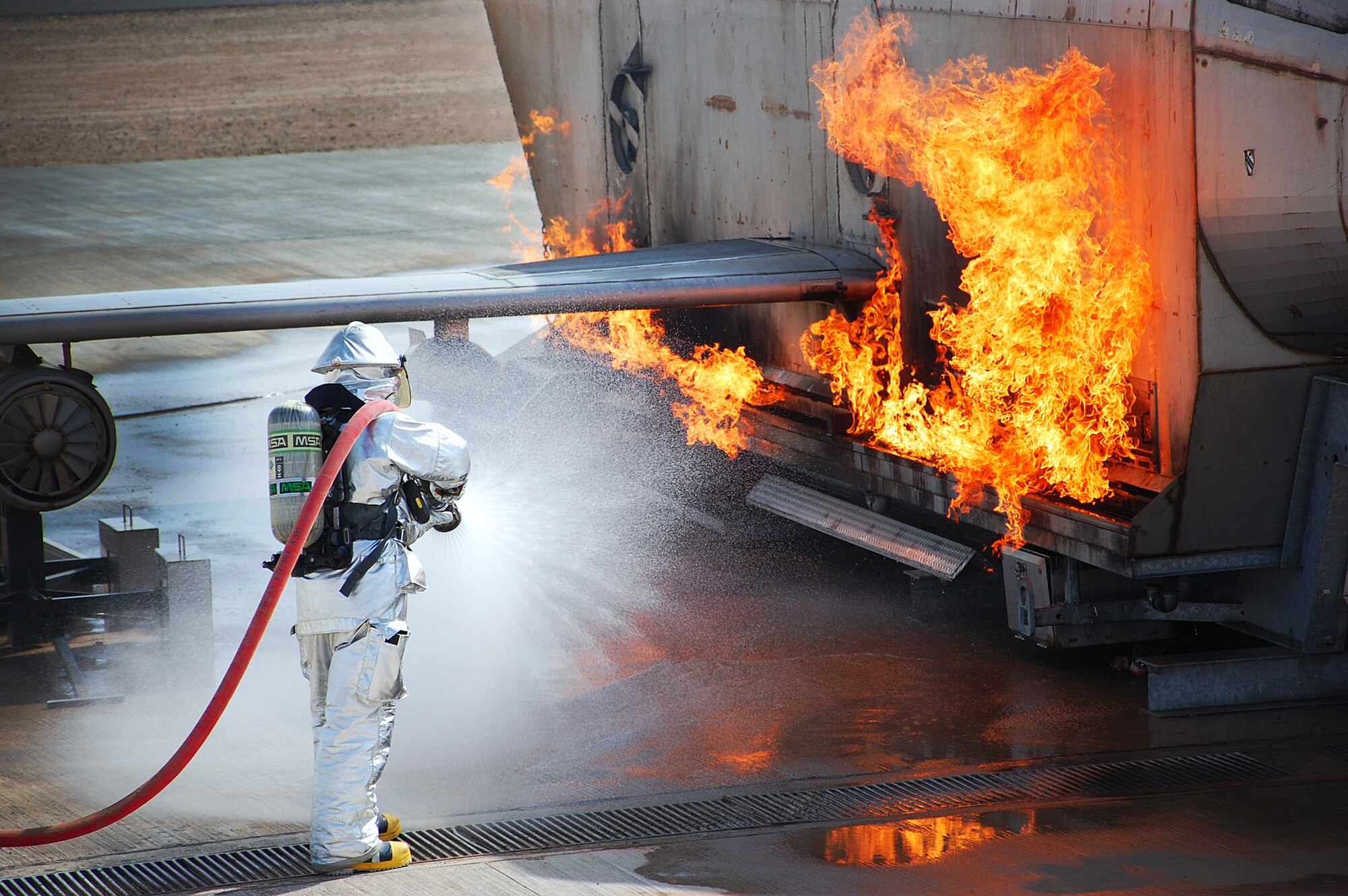 Senior Airman Buddy Roark adjusts the hoseline pattern just prior to extinguishing a simulated external fire during training in Southwest Asia March 26. Having the wide fog pattern sheilds heat allowing firefighters to get closer to the fire. Airman Roark is a firefighter with the 386th Expeditionary Civil Engineer Squadron. (U.S. Air Force photo by Senior Airman Cynthia Spalding)