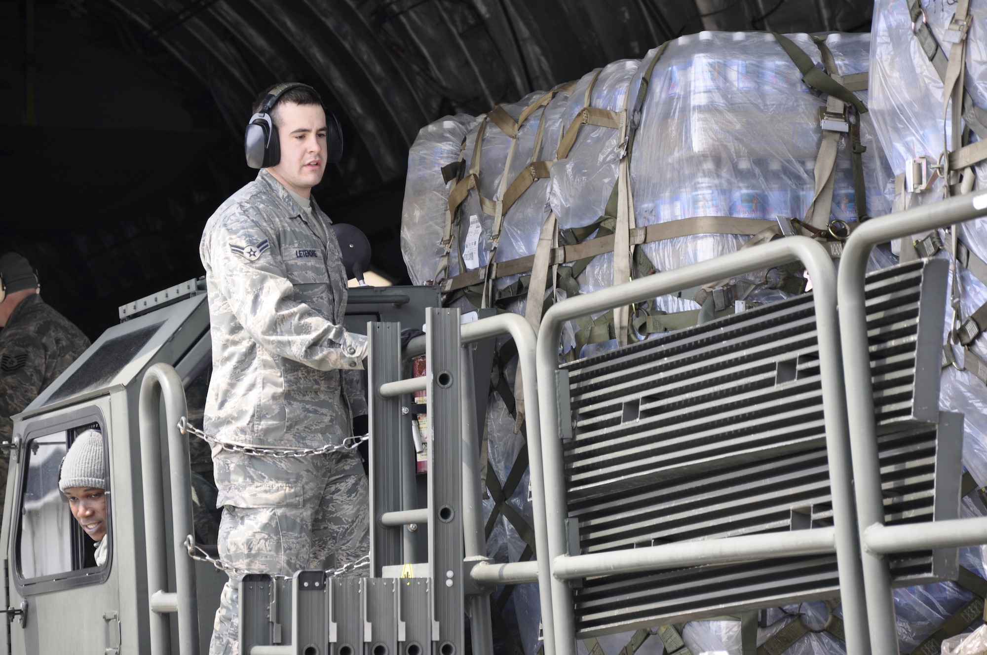 MISAWA AIR BASE, Japan -- Airman 1st Class Jeffrey Letendre, deployed from the 621st Contingency Response Wing at McGuire Air Force Base, N.J., helps guide pallets of water along a K loader, March 30. The U.S. Air Force C-17 Globemaster III, from March Air Reserve Base, Calif., delivered 87,000 pounds of water in support of Operation Tomodachi. (U.S. Air Force photo by Senior Airman Joe McFadden/Released)