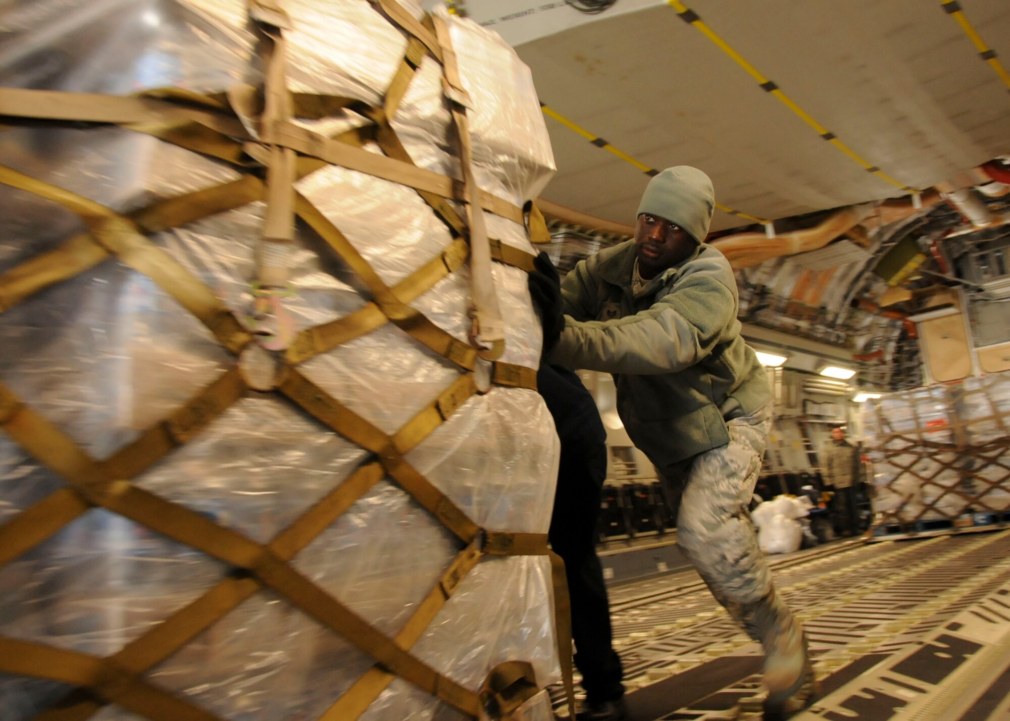 MISAWA AIR BASE, Japan -- Staff Sgt. Daine Burke, deployed to Misawa from the 515th Air Mobility Operations Wing at Hickam Air Force Base, Hawaii, pushes water pallets off of a U.S. Air Force C-17 Globemaster III, here March 30. This particular mission, flown in from March Air Reserve Base, Calif., delivered 87,000 pounds of water. (U.S. Air Force photo by Staff Sgt. Rachel Martinez/Released)