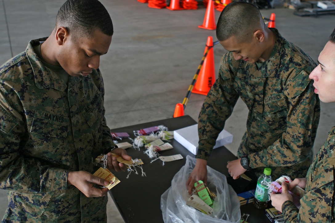 Lance Cpls. Nathaniel Haynes, Vincent Wong and Batista Ferrera, Installation Personnel Administration Center personnel clerks, sort through tags for identifying evacuees’ personal belongings during the Noncombatant Evacuation Operation exercise here March 31. The exercise tested the station’s ability to quickly, efficiently and effectively process residents in the event of a crisis.