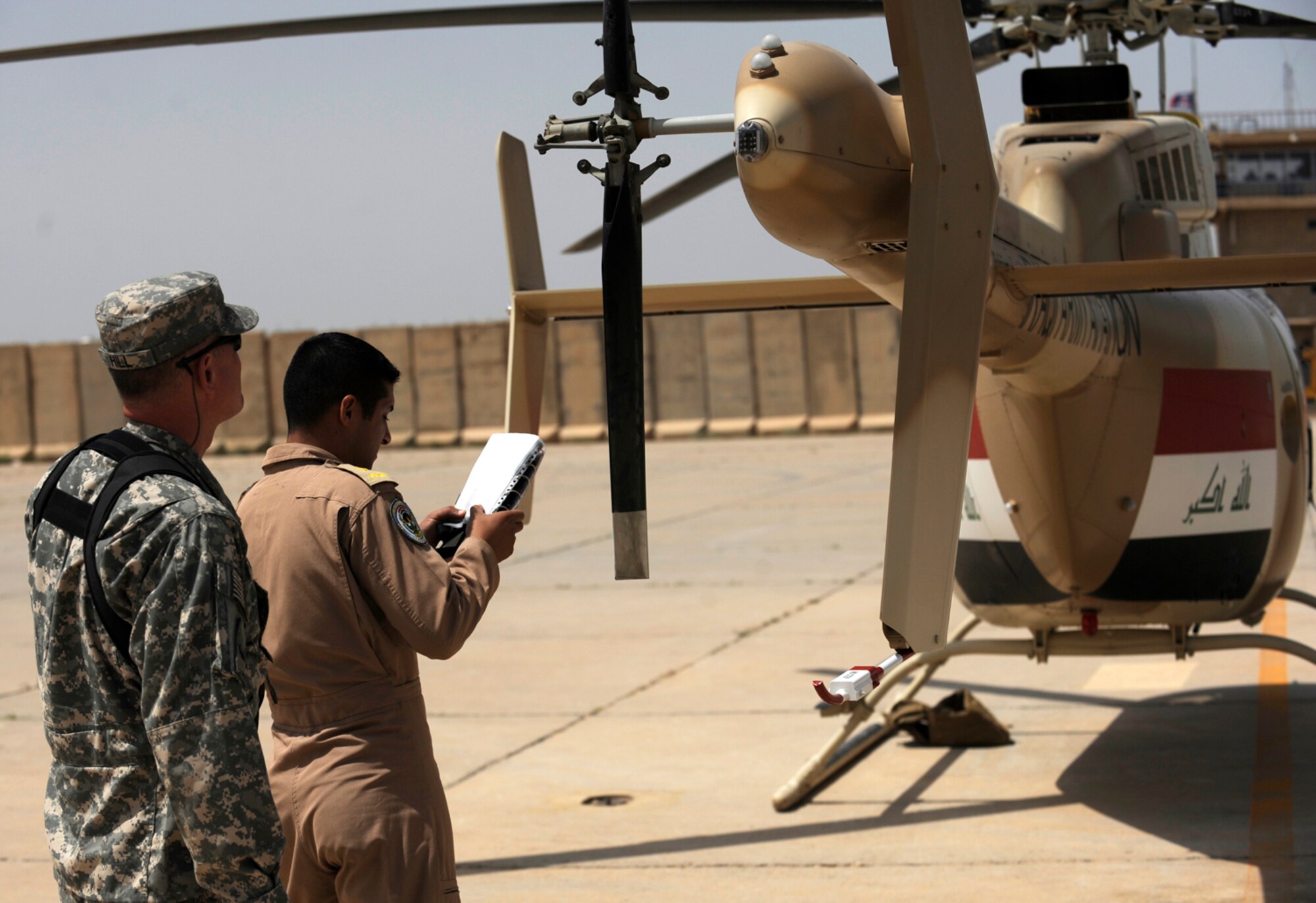 CAMP TAJI, Iraq -- Army Chief Warrant Officer Daniel Hill, left, a 721st Air Expeditionary Advisory Squadron T-407 instructor pilot, conducts pre-flight checks on the T-407 helicopter with an Iraqi Army Aviation Command co-pilot prior to a training mission April 28. Mr. Hill is a Nebraska National Guardsman from Grand Island. (U.S. Air Force/Tech. Sgt. Jason Lake)