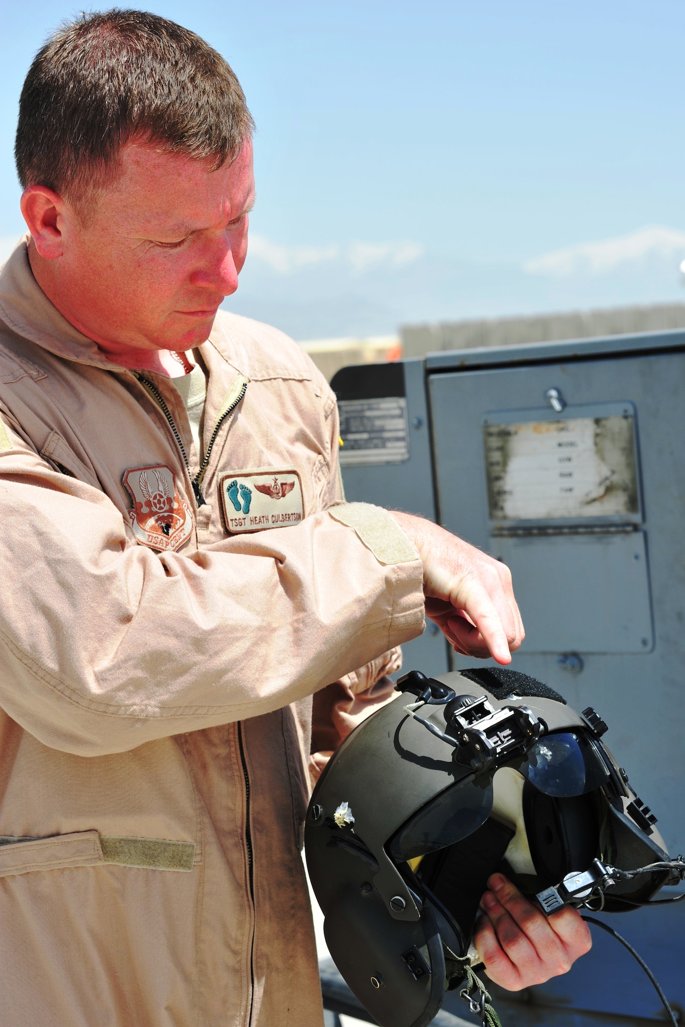 Tech. Sgt. Heath Culbertson, 83rd Expeditionary Rescue Squadron flight engineer, shows where a bullet entered then exited his helmet.  Sergeant Davis was uninjured when he was shot in the helmet during a mission to recover the pilots of a downed Army helicopter, April 23, 2011.  (U.S. Air Force photo by Capt. Erick Saks)