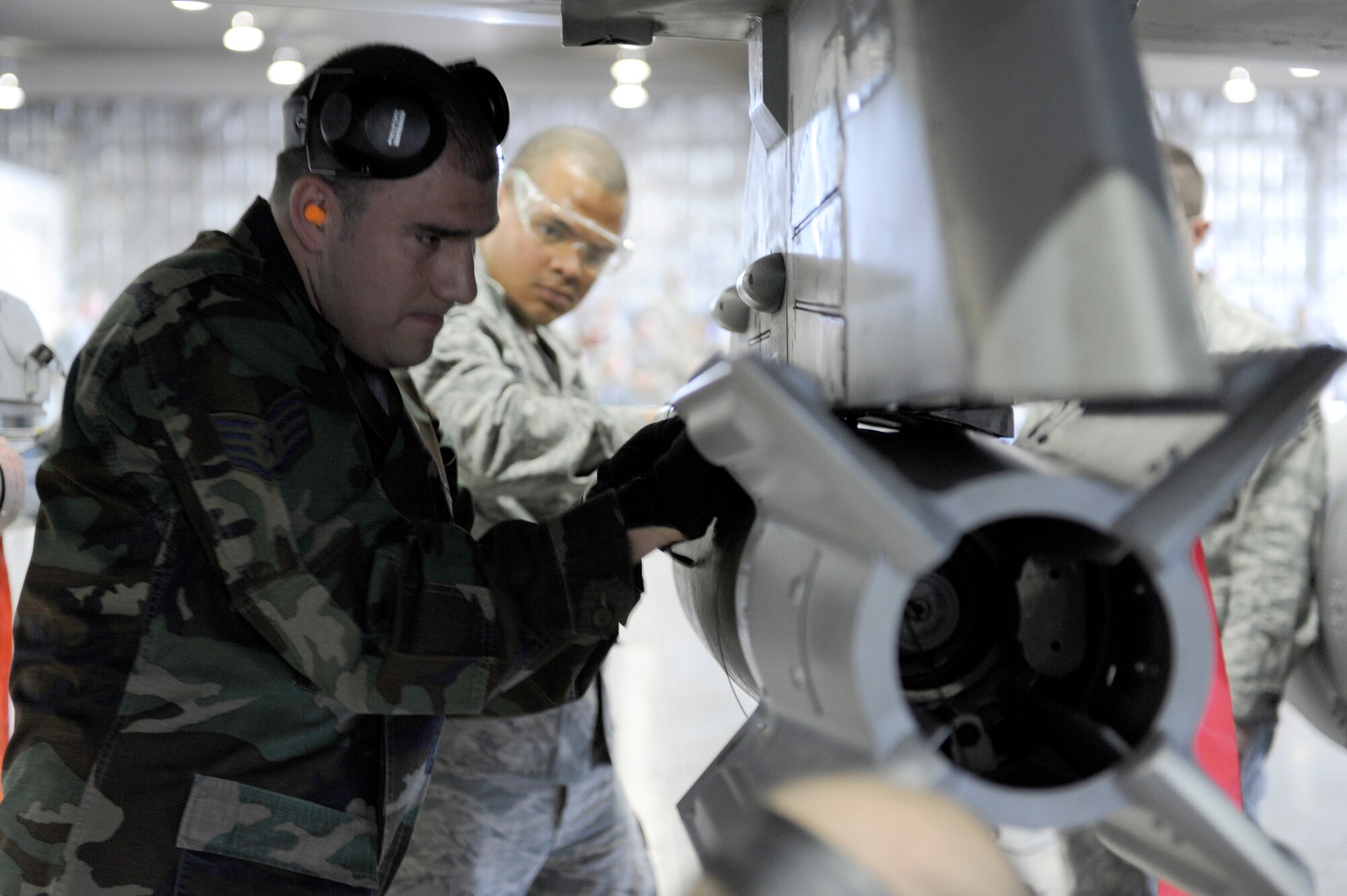 MISAWA AIR BASE, Japan -- Staff Sgt. Mark Drennen, front, and Airman 1st Class Robert Flowers-Velaquez, 35th Aircraft Maintenance Unit weapons load crew members, secures a Guided Bomb Unit-12 onto a pylon April 29. Each team was evaluated on their ability to properly load a GBU-12 and AIM-9 Sidewinder air-to-air missile. (U.S. Air Force photo/Staff Sgt. Marie Brown/Released)
