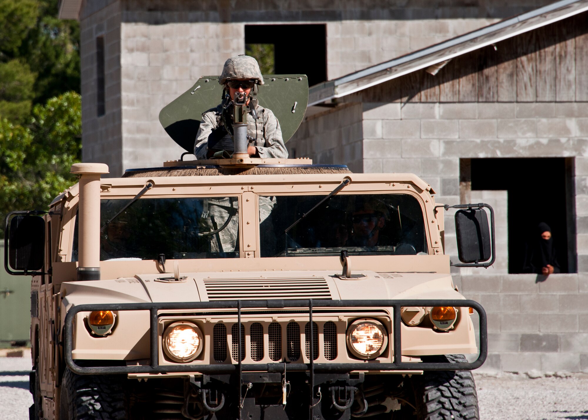 A mounted patrol rolls back toward their base as a ‘local’ villagers watch during an exercise April 28 at Eglin Air Force Base, Fla.  This was part of Air Force Materiel Command’s "Brave Defender" training, which is administered by the 96th Ground Combat Training Squadron.  Teams of Airmen experienced both mounted (vehicle) and dismounted (foot) patrols through the forests and simulated villages around their base.  GCTS instructors push 10 training classes a year, which consists of improvised explosive device detection and reaction, operating in an urban environment, mission planning, land navigation and casualty care. The three-week training culminates with a three-day field training exercise where the Airmen apply what they learned in combat scenarios.  More than 140 Airmen from more than 12 locations attended this training.  (U.S. Air Force photo/Samuel King Jr.)