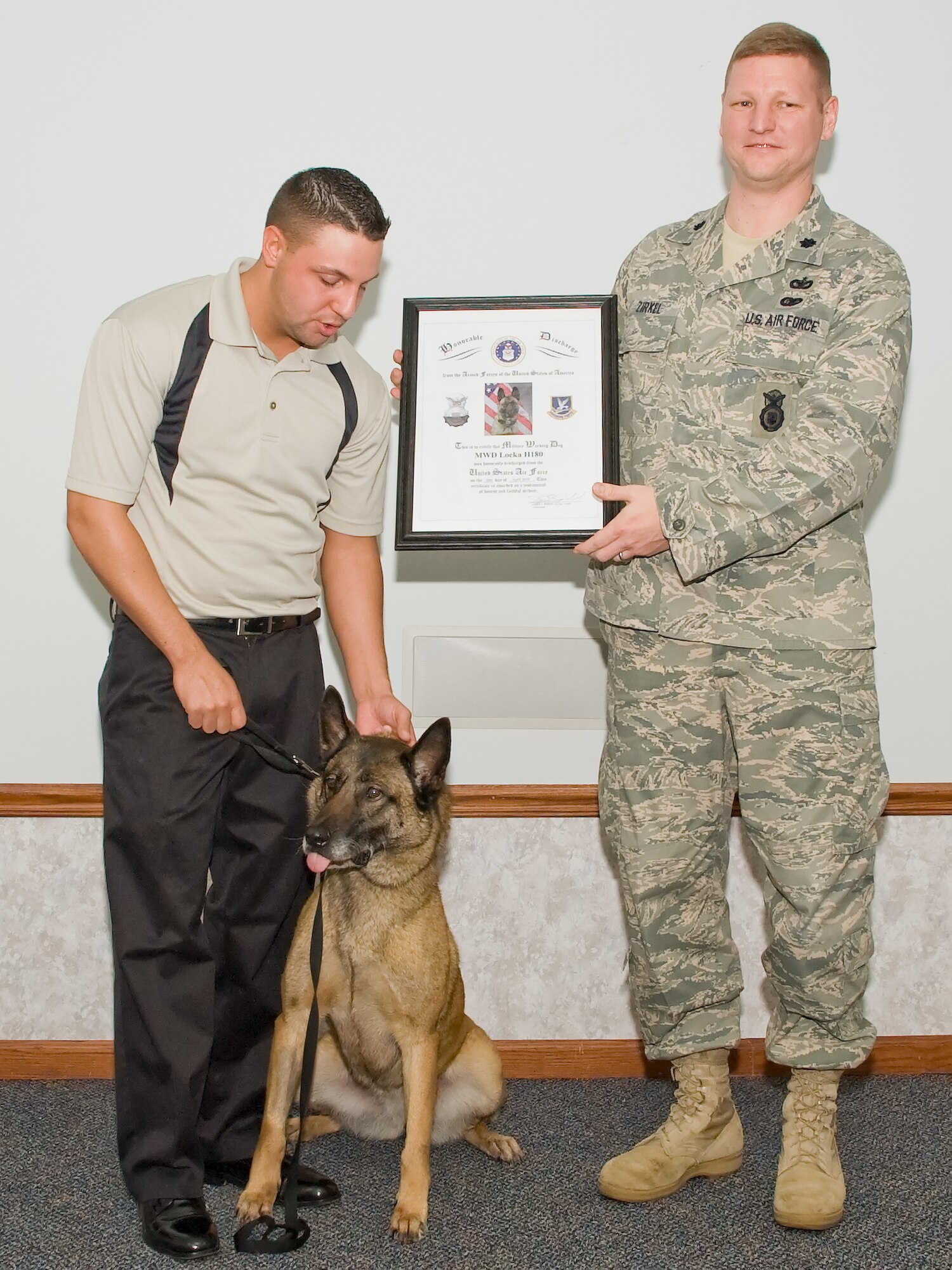 Military Working Dog Loeka and her former handler, John Leonard, are presented a certificate in recognition of Loeka’s six years of service at her retirement ceremony April 28, 2011, at Dover Air Force Base, Del. Over the years, Loeka has been on three deployments to Iraq, saving numerous lives. (U.S. Air Force photo by Adrian Rowan)   