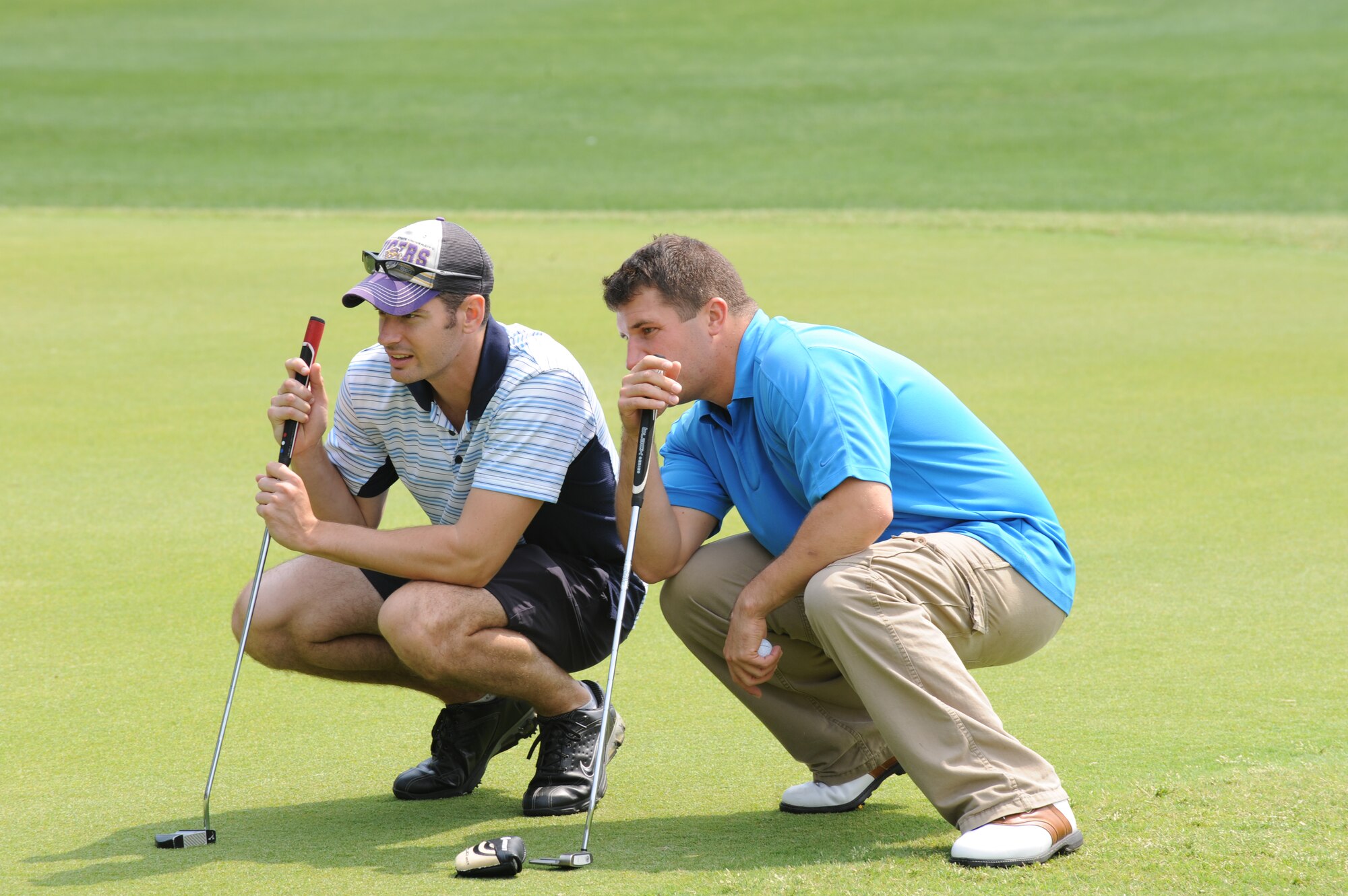 John Belt and Bret Deroche, 34th Special Operations Squadron, figure out the best way to putt on the green during a tournament at Gator Lakes Golf Course on Hurlburt Field, Fla., April 15, 2011. The tournament was part of the 4th Annual Golf Scramble hosted by the Hurlburt Field Spouses' Club. (DOD photo by Airman 1st Class Caitlin O'Neil-McKeown/RELEASED) 