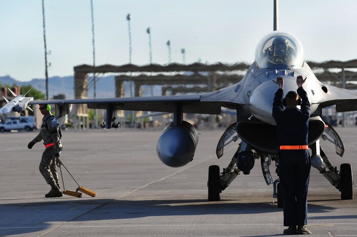 NELLIS AIR FORCE BASE, Nev. --  Airman 1st Class Jason Kilby, weapons loader, from the 20th Aircraft Maintenance Squadron, Shaw Air Force Base, S.C., pulls the chocks from an F-16 Fighting Falcon while Airman 1st Class Jeremy Andrews, a crew chief from the 79th Aircraft Maintenance Squadron, prepares to marshal a F-16 Fighting Falcon out for a training mission during Green Flag West 11-6, April 28.  Green Flag West replicates irregular warfare conditions currently found in Southwest Asia. Aircrews, work closely with Air Force joint terminal attack controllers. Pilots train for a missions such as close air support, and aerial reconnaissance.  (U.S. Air Force photo by Staff Sgt. William P.Coleman)  