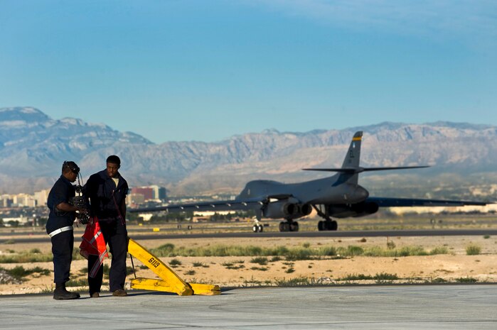 NELLIS AIR FORCE BASE, Nev. --  Airman 1st Class Samuel Carr and Senior Airman Quincee Baker, crew chief, 28th Aircraft Maintenance Squadron, Ellsworth AFB, S.D., pick up chocks after marshalling out a B-1 Lancer during exercise Green Flag West 11-6, April 28. Green Flag West replicates irregular warfare conditions currently found in Southwest Asia. Aircrews, work closely with Air Force joint terminal attack controllers. Pilots train for a missions such as close air support, and aerial reconnaissance.(U.S. Air Force photo by Senior Airman Brett Clashman)