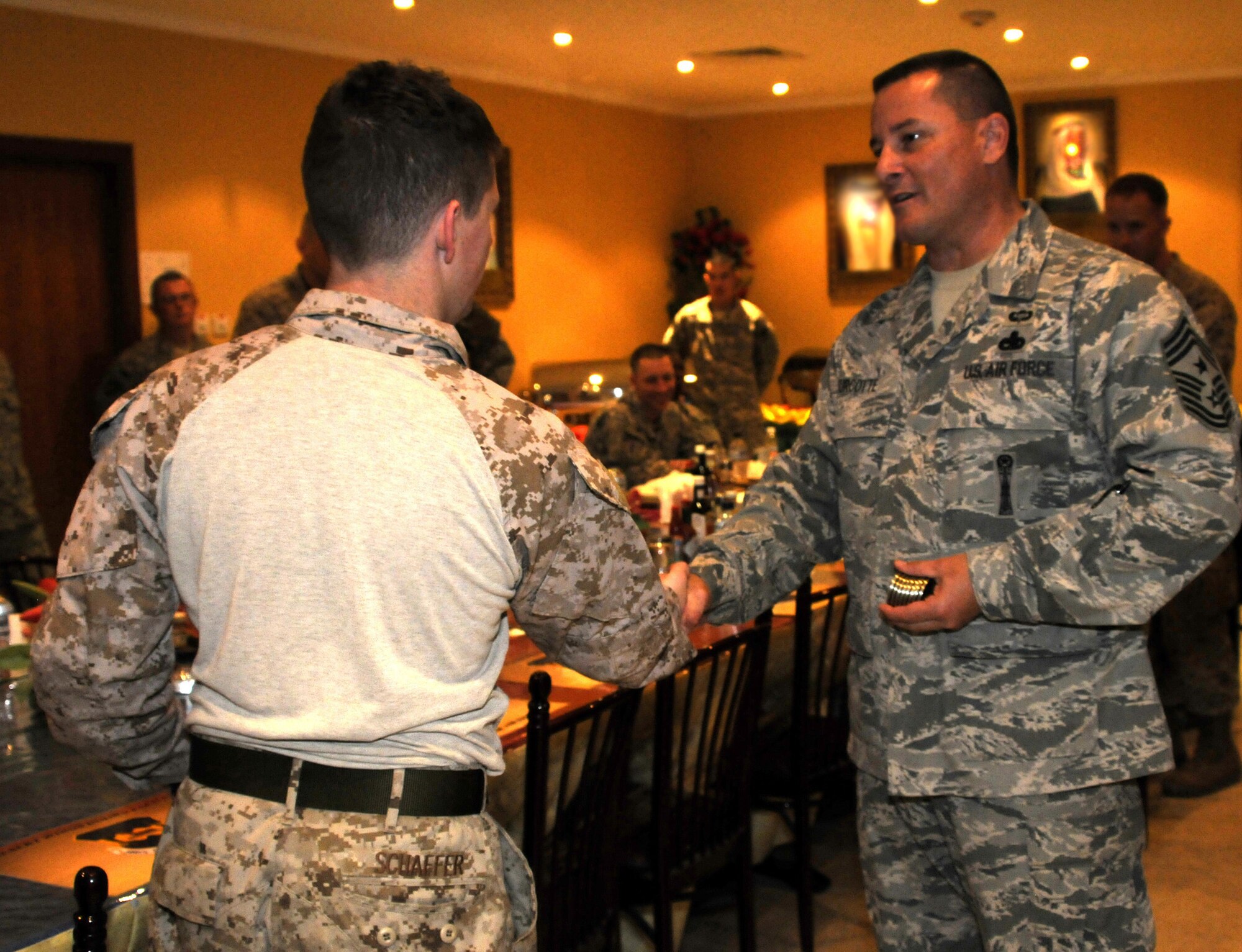 Command Chief Master Sgt. Richard Turcotte, 386th Air Expeditionary Wing command chief, gives a coin to Marine Corporal Isaiah Shaffer at the 386th's Desert Winds Dining Hall May 1. Corporal Shaffer was part of Operation Proper Exit, a program put together by the Troops First Foundation and the United Service Organization. The objective of the program is to bring closure to veterans wounded in combat and to show troops in the war zone that injuries sustained in battle are surmountable. (U.S. Air Force photo by Capt. Heath Allen)