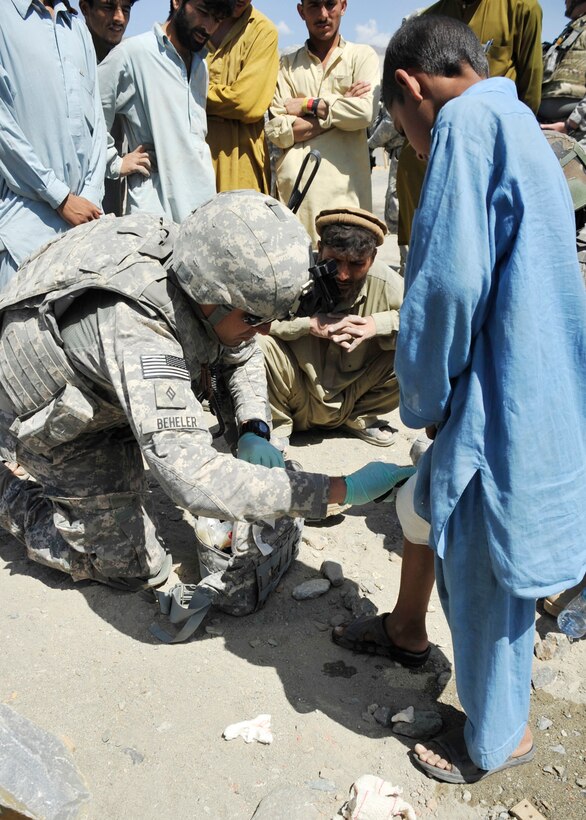 Navy Seaman James Q. Beheler, a corpsman with the provincial reconstruction team in Afghanistan’s Kunar province, puts a bandage on an Afghan boy’s leg at Zagrano Bando School, April 14, 2011. Beheler noticed the boy was wearing a makeshift bandage after being bitten by a dog the previous day, and he changed the boy’s bandage to help in preventing infection. U.S. Air Force photo by Tech. Sgt. Chuck Walker