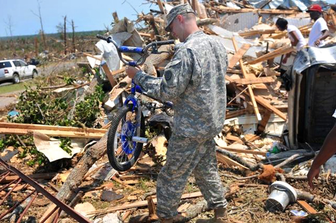U.S. Army Spc. Robert Boettner carries a child's bike from the rubble of a home in the Crescent Ridge area of Tuscaloosa, Ala., April 30, 2011. Boettner is assigned to the 31st Chemical Brigade.