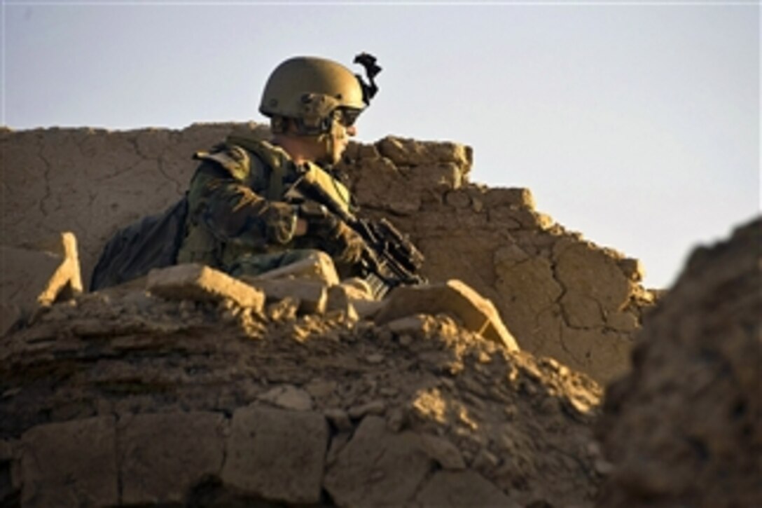 A U.S. Special Operations soldier provides security overwatch from a rooftop during the early morning hours of a clearing operation in Panjwa'i District in Kandahar province, Afghanistan, on April 25, 2011.  