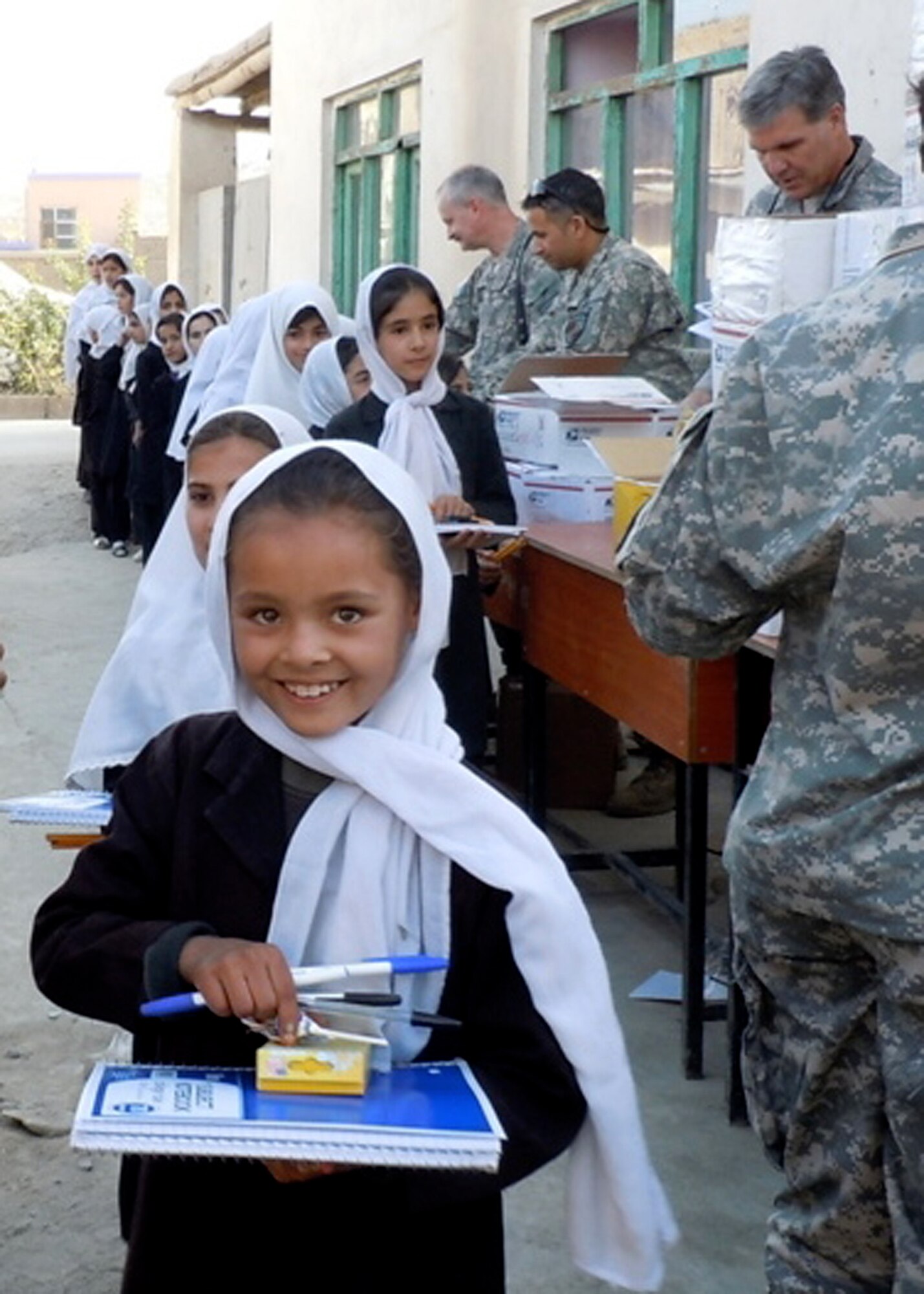 Col. Bob Wicks (top right) and other members of Regional Support Command-Capital hand out supplies to young girls at a school in Kabul, Afghanistan, during Colonel Wicks’ year-long deployment as the Regional Support Command-Capital commander. He and the other RSC-Capital military servicemembers adopted this girls’ school and donated tents and supplies from care packages sent by family and friends. He is deployed from the 13th Air Force at Joint Base Pearl Harbor-Hickam, Hawaii. (Courtesy photo)