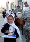 Col. Bob Wicks (top right) and other members of Regional Support Command-Capital hand out supplies to young girls at a school in Kabul, Afghanistan, during Colonel Wicks’ year-long deployment as the Regional Support Command-Capital commander. He and the other RSC-Capital military servicemembers adopted this girls’ school and donated tents and supplies from care packages sent by family and friends. He is deployed from the 13th Air Force at Joint Base Pearl Harbor-Hickam, Hawaii. (Courtesy photo)