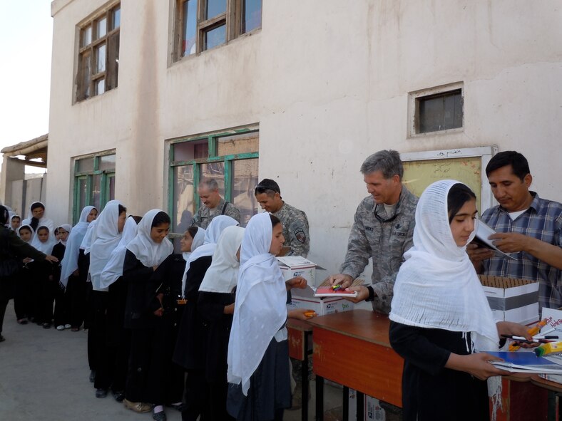 Col. Bob Wicks and other members of Regional Support Command-Capital hand out supplies to young girls at a school in Kabul, Afghanistan, during Colonel Wicks’ year-long deployment as the Regional Support Command-Capital commander. He and the other RSC-Capital military servicemembers adopted this girls’ school and donated tents and supplies from care packages sent by family and friends. He is deployed from the 13th Air Force at Joint Base Pearl Harbor-Hickam, Hawaii. (Courtesy photo)
