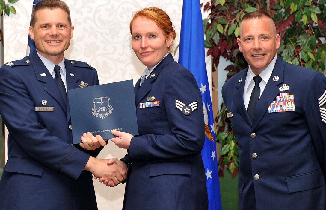 Senior Airman Doris Ritchey, accepts  her Community College of the Air Force diploma from Col. MIchael Hornitschek, commander, 375th Air Mobility Wing, at graduation ceremonies held at Scott Air Force Base, Il.  Airman Ritchey received an associates' degree in information management. She is assigned to the 932nd Airlift Wing information management flight. Standing right, is 375th AMW Command Chief Master Sgt. Kevin Candler.  (Courtesy photo)