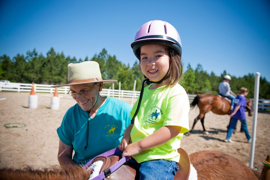 Ansley Dickenson smiles for the camera while receiving a horse ride with assistance from Carol Norris April 30 at Jacobs’ Ladder Therapeutic Riding Center in Hahira, Ga. Ansley and her family have been utilizing the facility for two years. Ms. Norris has been volunteering at the facility for nine years. (U.S. Air Force photo/Staff Sgt. Jamal D. Sutter)(RELEASED)