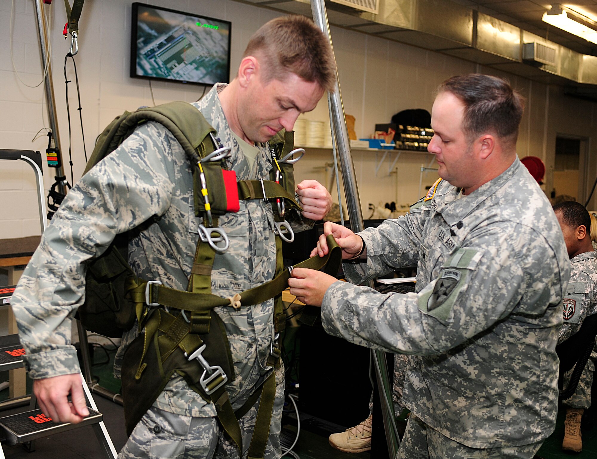 U.S. Army Sgt. Jonathan Copley, the Joint Communications Support Element parachute pack ncoic, assists Capt. Raymond Funke, the 56th Medical Information Systems flight commander, with parachute simulation training during the Air Force Company Grade Officer Professional Development Conference tour of the joint parachute facility at MacDill Air Force Base, Fla., May 3, 2011. The conference theme is “Culture-Competence-Leadership; Joint Airmen for Tomorrow’s Battlefield” focusing on providing junior officers with a greater awareness of current operations, the culture and customs of tribal regions in Afghanistan and Pakistan, and the myriad of leadership opportunities in Total Force and joint environments. 
 (U.S. Air Force photo by Senior Airman Linzi Joseph/Released)
