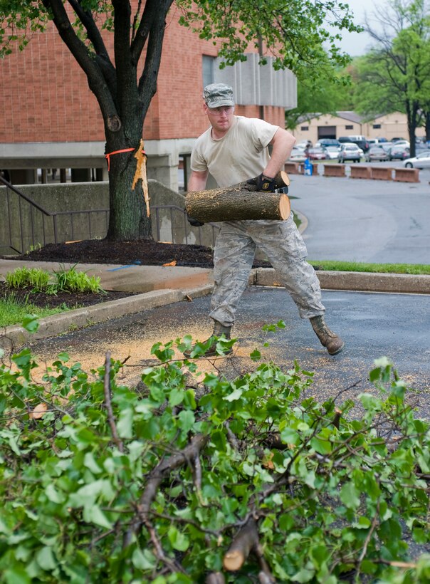 Senior Airman Matthew Travis,11th Civil Engineer Squadron heavy pavement and equipment operator, muscles a tree limb that he cut from a downed tree branch next to the 11th Wing headquarters building April 28. Airman Travis was one of several 11 CES Airmen and civilian personnel deployed to various areas around Joint Base Andrews to clean up downed trees and reenergize power lines left by recent tornado winds that briefly touched down here April 27. (Photo by Bobby Jones) 
