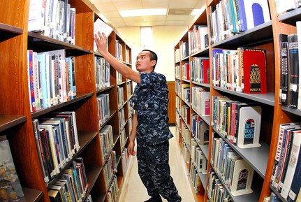 Machinist’s Mate 3rd Class Michael Phaiboun, Naval Support Activity, reaches for a book at the Joint Base Charleston - Weapons Station Branch Library May 3. The Branch Library has undergone facility enhancements and improvements in customer service.  (U.S. Navy photo/Machinist’s Mate 3rd Class Brannon Deugan)