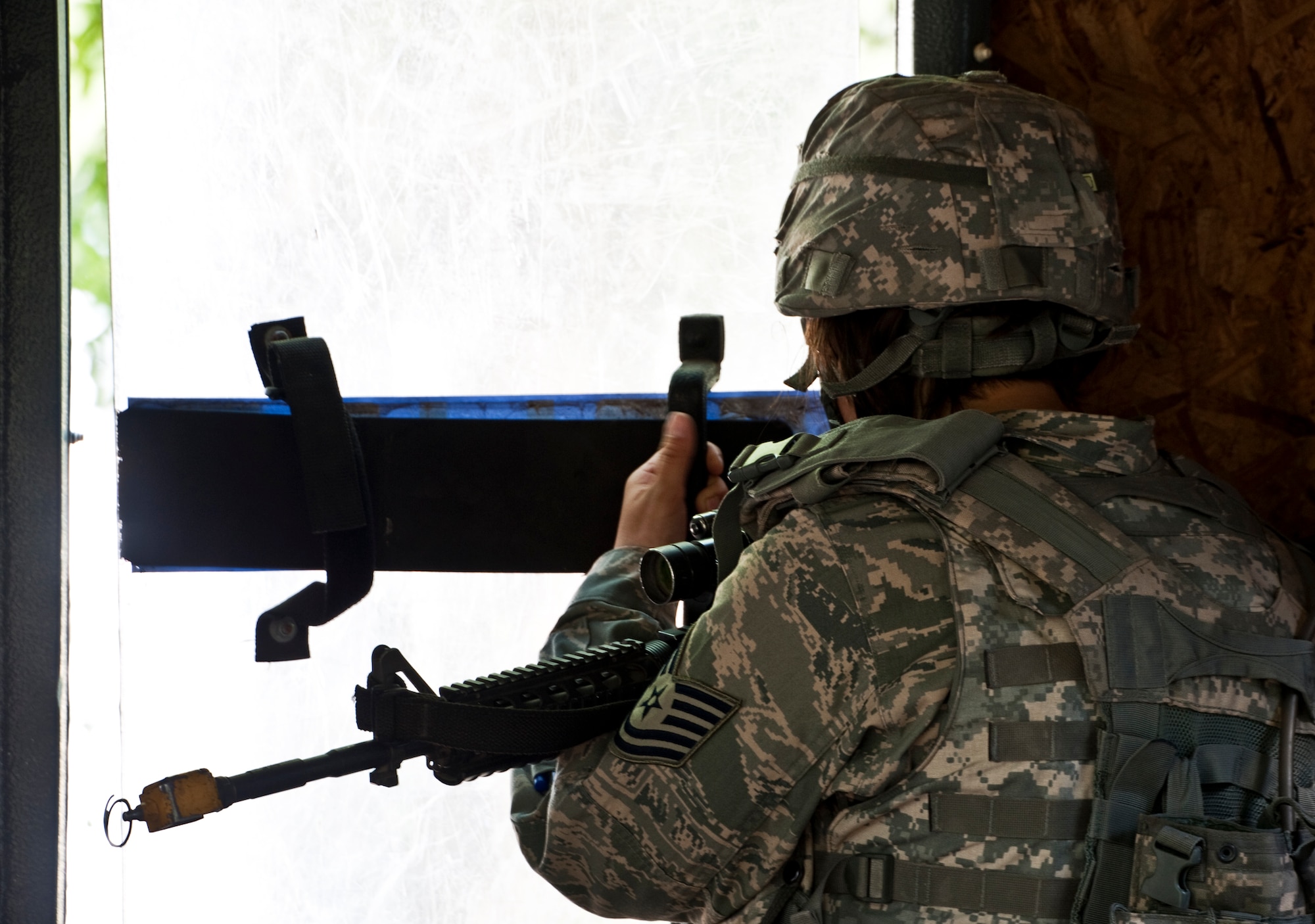 A security forces Airman watches from behind a riot shield during guard duty at the entry control point April 29 at Eglin Air Force Base, Fla.  This was part of Air Force Materiel Command’s "Brave Defender" training, which is administered by the 96th Ground Combat Training Squadron.  ECP guards experienced random vehicle inspections, media visits and vehicle-borne improvised explosive device during posted shifts.   GCTS instructors push 10 training classes a year, which consists of IED detection and reaction, operating in an urban environment, mission planning, land navigation and casualty care.  The three-week training culminates with a three-day field training exercise where the Airmen apply what they learned in combat scenarios.  More than 140 Airmen from more than 10 locations attended this training.  (U.S. Air Force photo/Samuel King Jr.)