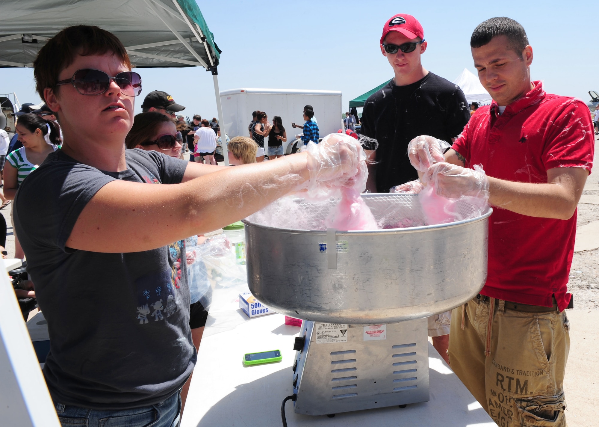 ABILENE, Texas ? (left to right) Staff Sgt. Tanya Sullivan, Airman 1st Class John Thornton and Staff Sgt. David Williams, 7th Maintenance Operations Squadron, make cotton candy to raise money for their unit advisory council April 30 at the Dyess Big Country Airfest here. The airfest is held at Abilene Regional Airport every other year and features various aircraft performances as well as static displays. The airfest is held to bring the Abilene and Dyess communities together and to demonstrate Air Force capabilities. (U.S. Air Force photo/ Senior Airman Chelsea Cummings)