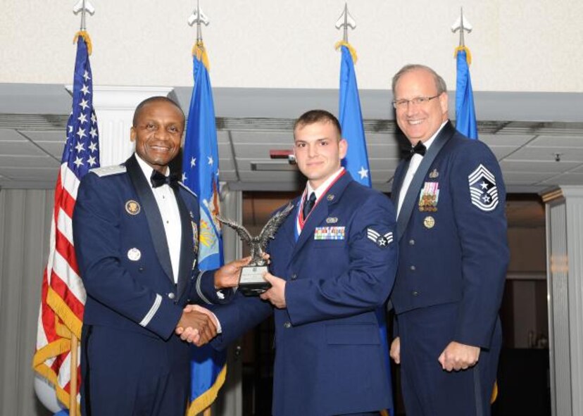 844th Communications Group Airfield Systems Journeyman Senior Airman Richard Prestia accepts an award for Airman of the Year and Military Volunteer of the Year, presented by Air Force District of Washington Commander Maj. Gen. Darren McDew and AFDW Command Chief Master Sgt. Pat Battenberg. The banquet was held at The Club on Joint base Anacostia-Bolling, April 29. (USAF Photo by Senior Airman Matthew Coleman-Foster)
