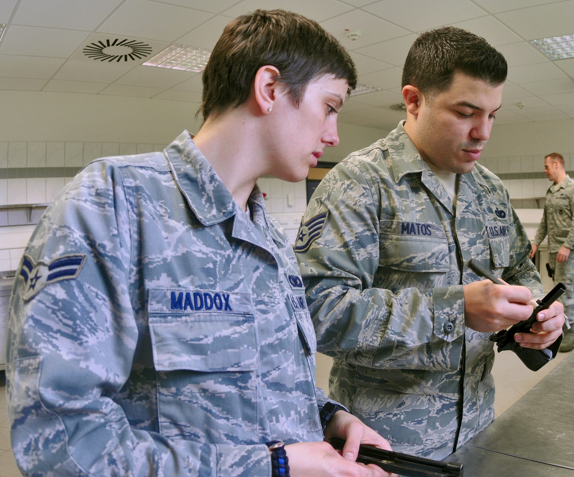 SPANGDAHLEM AIR BASE, Germany – Staff Sgt. Cesar Matos, 52nd Security Forces Squadron combat arms instructor, inspects the M-9 pistol of Airman 1st Class Charla Maddox, 52nd SFS patrolman, during weapons qualification training here April 28. Security forces Airmen are required to qualify on their weapons biannually. (U.S. Air Force photo/Senior Airman Nick Wilson)