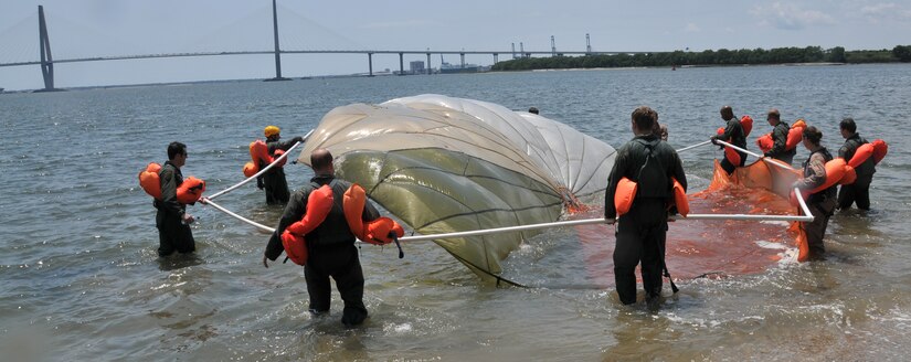 Ten Airmen from Joint Base Charleston carry a parachute from the shore to the water during a seven-hour long Water Survival Training Course May 2, at the Charleston Harbor. The students had to pull themselves from under the parachute by finding a line and pulling themselves free. (U.S. Air Force photo /Airman 1st Class Jared Trimarchi)