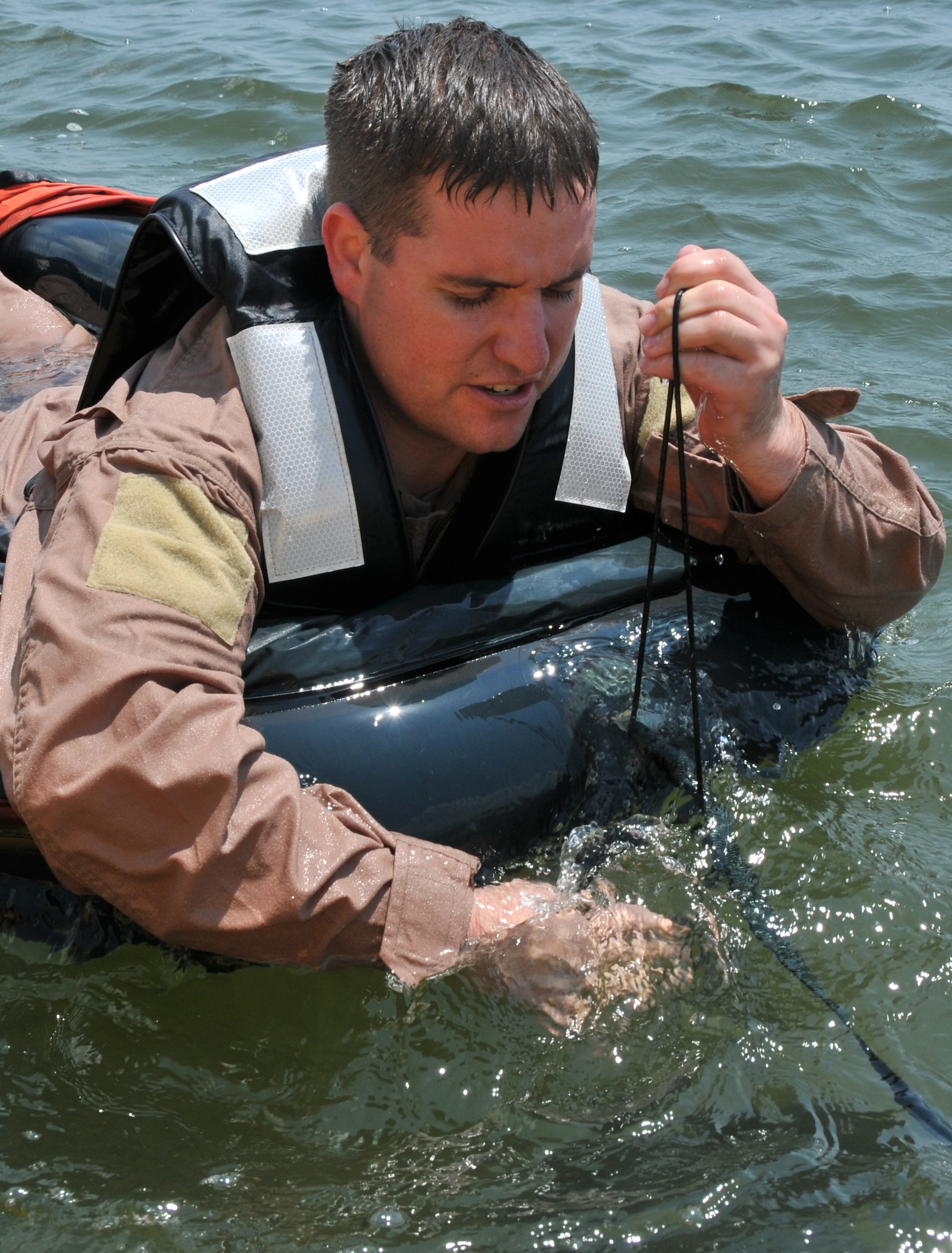 Staff Sgt. Anthony Barrette, Survival Evasion Resistance Escape specialist from the 437th Operations Support Squadron, pulls up an anchor attached to the front of a one-man life raft during a Water Survival Training course May 2, at the Charleston Harbor. During the course each Airman must board the life raft and show the location of the anchor and air valves. (U.S. Air Force photo /Airman 1st Class Jared Trimarchi)
