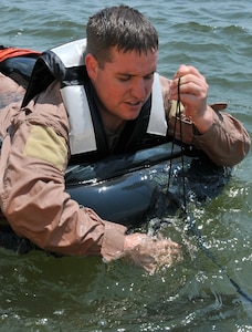 Staff Sgt. Anthony Barrette, Survival Evasion Resistance Escape specialist from the 437th Operations Support Squadron, pulls up an anchor attached to the front of a one-man life raft during a Water Survival Training course May 2, at the Charleston Harbor. During the course each Airman must board the life raft and show the location of the anchor and air valves. (U.S. Air Force photo /Airman 1st Class Jared Trimarchi)
