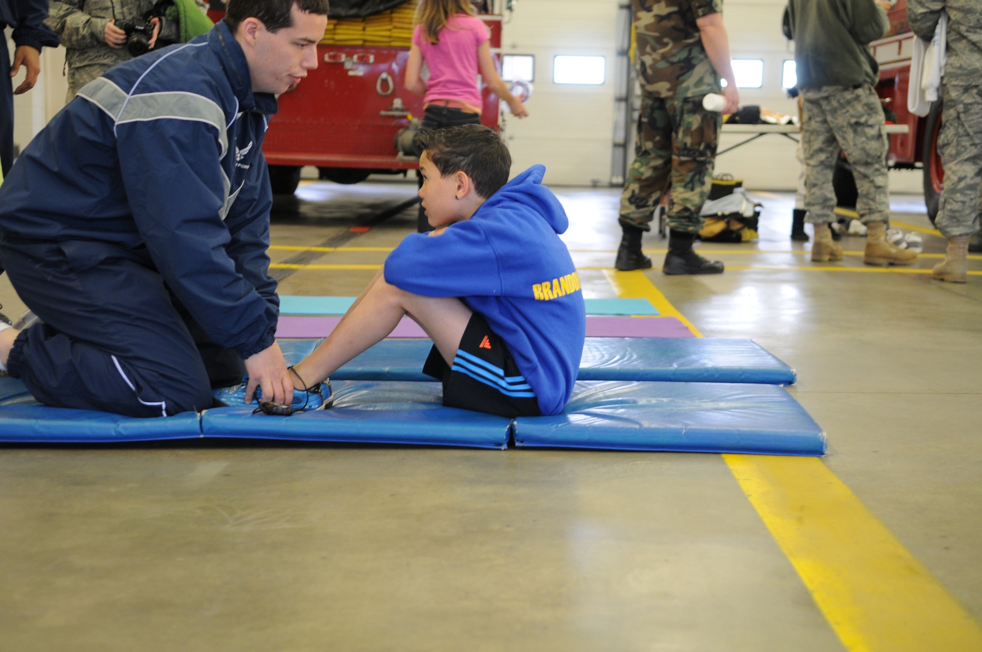 RAF MILDENHALL, England -- Airman 1st Class Scott McDermitt, 100th Force Support Squadron fitness center staff, counts the sit ups of Cejay Coleman, 11, son of Tech. Sgt. Corey Coleman, during RAF Mildenhall's Job Shadow Day here April 28, 2011. This image was taken by a JSD participant as well. The 7-year-old is the son of 100th Air Refueling Wing Public Affairs Staff Sgt. Thomas Trower. (U.S. Air Force photo/Scott Trower)