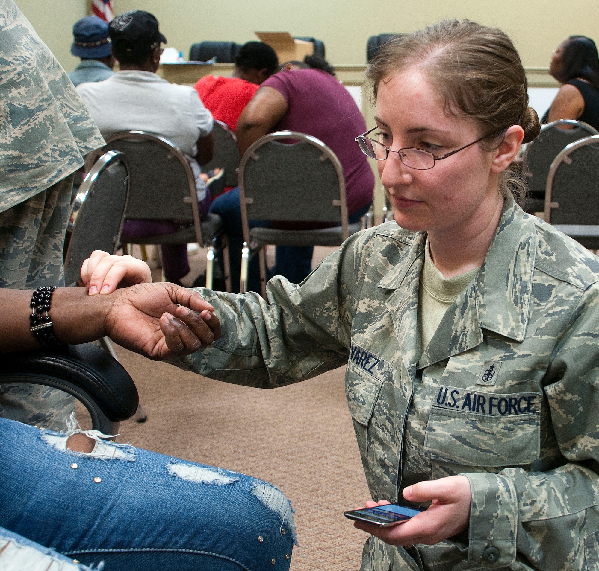 HAYNEVILLE, Ala. -- Master Sgt. Jessica Alvarez, a medical technician with the Alaska Air National Guard's 176th Medical Group, uses an iPhone and a steady hand to take a patient's pulse at a free medical clinic here May 3, 2011. Twenty-five members of the medical group (together with 10 support personnel from other Alaska Air Guard units) arrived here May 1 for 12 days of training through the Innovative Readiness Program. This program allows Guard and Reserve members to get the training they need while at the same time delivering real-world results -- in this case, providing an array of health-care services to a historically underserved area. Alaska Air National Guard photo by Capt. John Callahan.