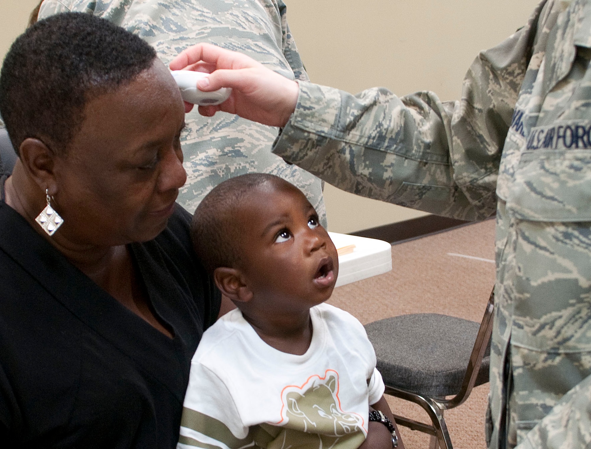 HAYNEVILLE, Ala. -- A young Hayneville resident watchs Master Sgt. Jessica Alvarez take his mother's temperature at a free medical clinic here May 3, 2011. Twenty-five members of the medical group (together with 10 support personnel from other Alaska Air Guard units) arrived here May 1 for 12 days of training through the Innovative Readiness Program. This program allows Guard and Reserve members to get the training they need while at the same time delivering real-world results -- in this case, providing an array of health-care services to a historically underserved area. Alaska Air National Guard photo by Capt. John Callahan.