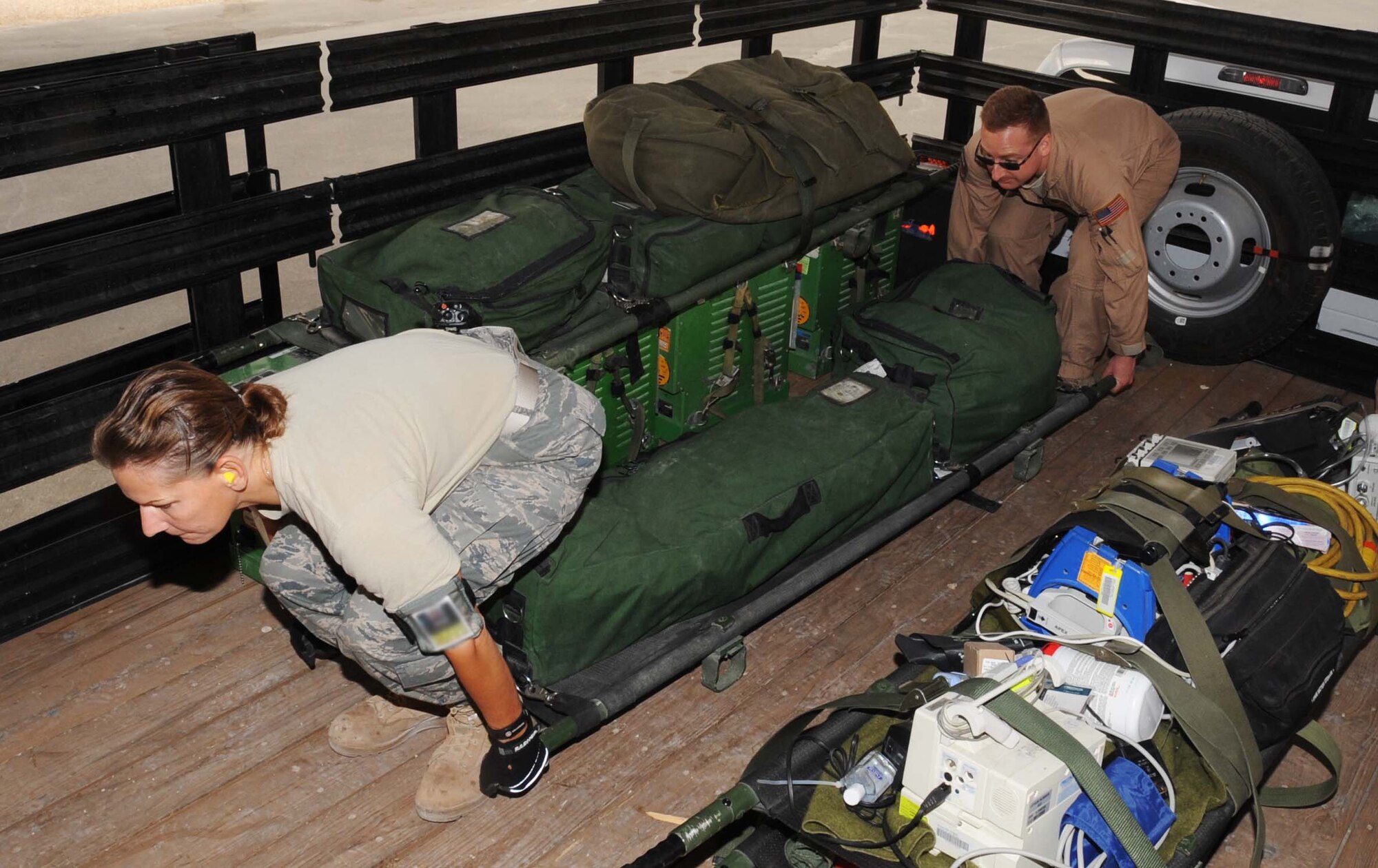 Tech. Sgt. Christine Penska and Staff Sgt. Samuel Zito III prepare to carry a litter into the back of a C-130 May 4 in Southwest Asia.(U.S. Air Force photo/ Staff Sgt. Anthony Graham)