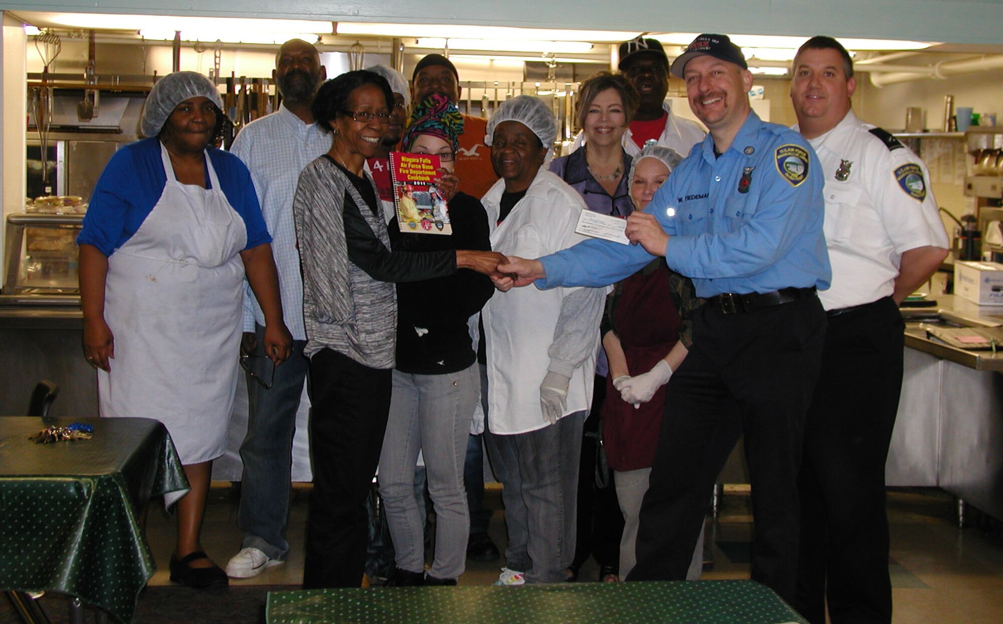Niagara Falls Air Reserve Station Fire Inspector (far left) and  Firefighter William Tiedeman donate a check for $1,200 to the Niagara Falls City Mission April 29, 2011.
The firemen raised the money for the mission by selling cook books that contained firefighters various homemade recipes.