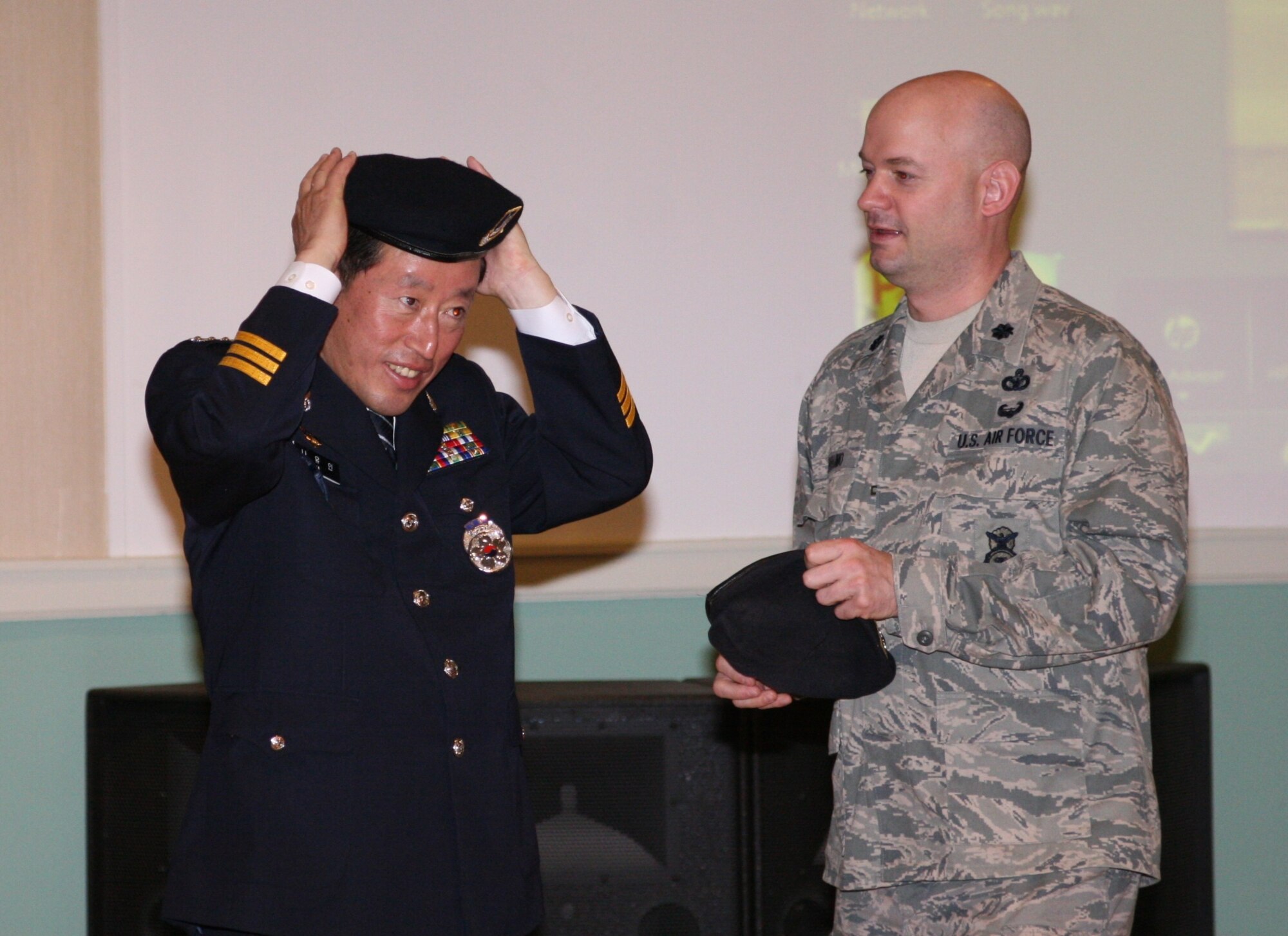 KUNSAN AIR BASE, Republic of Korea -- Chief Na Yu-In, Gunsan Korean National Police chief, puts on an 8th Security Forces Squadron beret that Lt. Col. Mark Anarumo, 8th SFS commander, gave him following a lunch and briefing by Chief Na at the Loring Club here May 3. Chief Na and Colonel Anarumo planned the event after they met and found a common bond in education, which they realized could benefit both of their forces. Colonel Anarumo plans to address the Gunsan City police in June. (Courtesy photo)