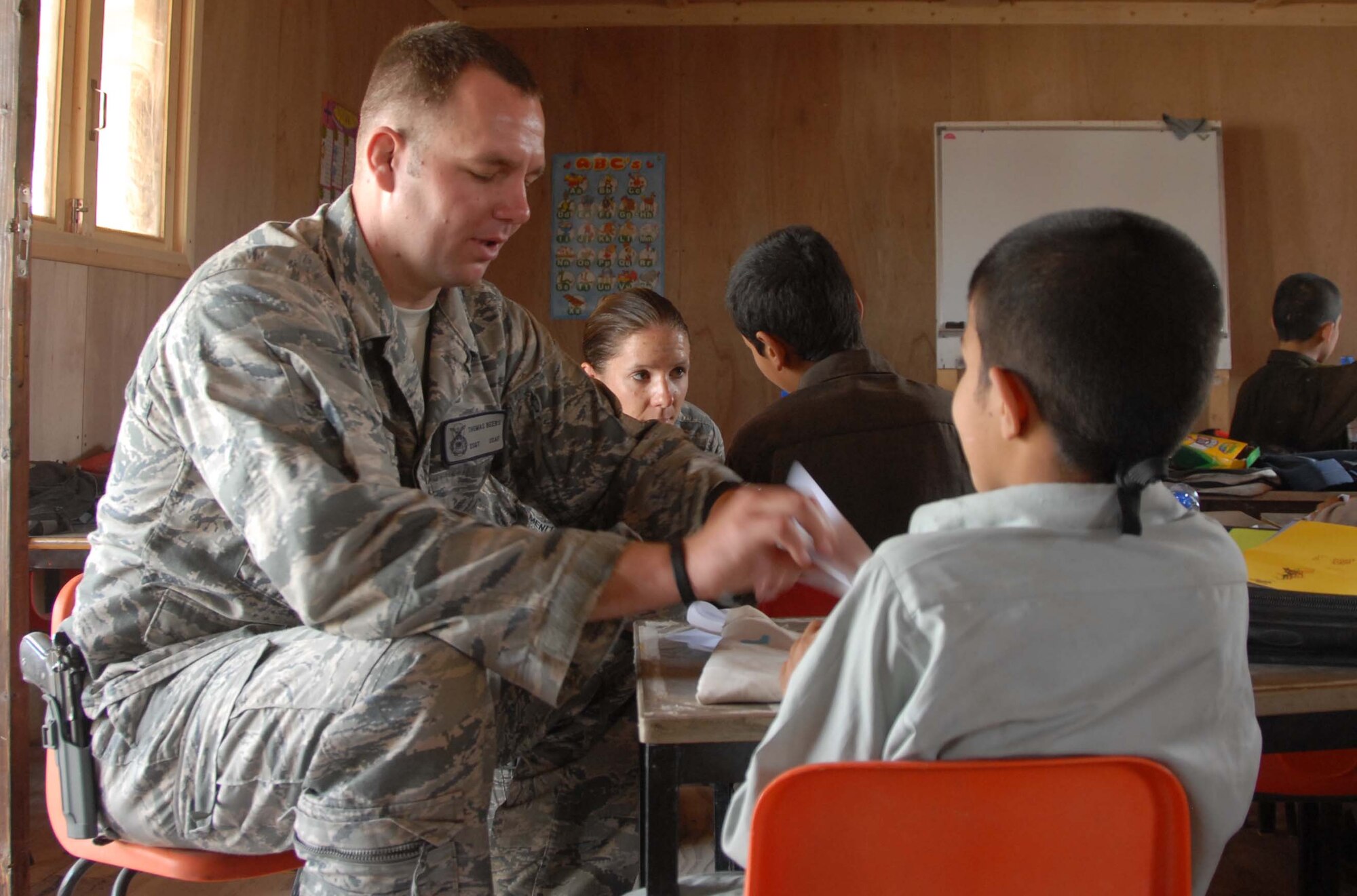 Staff Sergeant Thomas Beers and Staff Sergeant Amanda Menlove demonstrate how to build paper airplanes to Afghan boys at a school at Kandahar Airfield, Afghanistan on April 30, 2011. The two were part of a group of noncommissioned officers who volunteered to spend the day with the children and participate in activities such as the building the paper airplanes and playing soccer. (Photo by Tech. Sgt. Emily F. Alley)