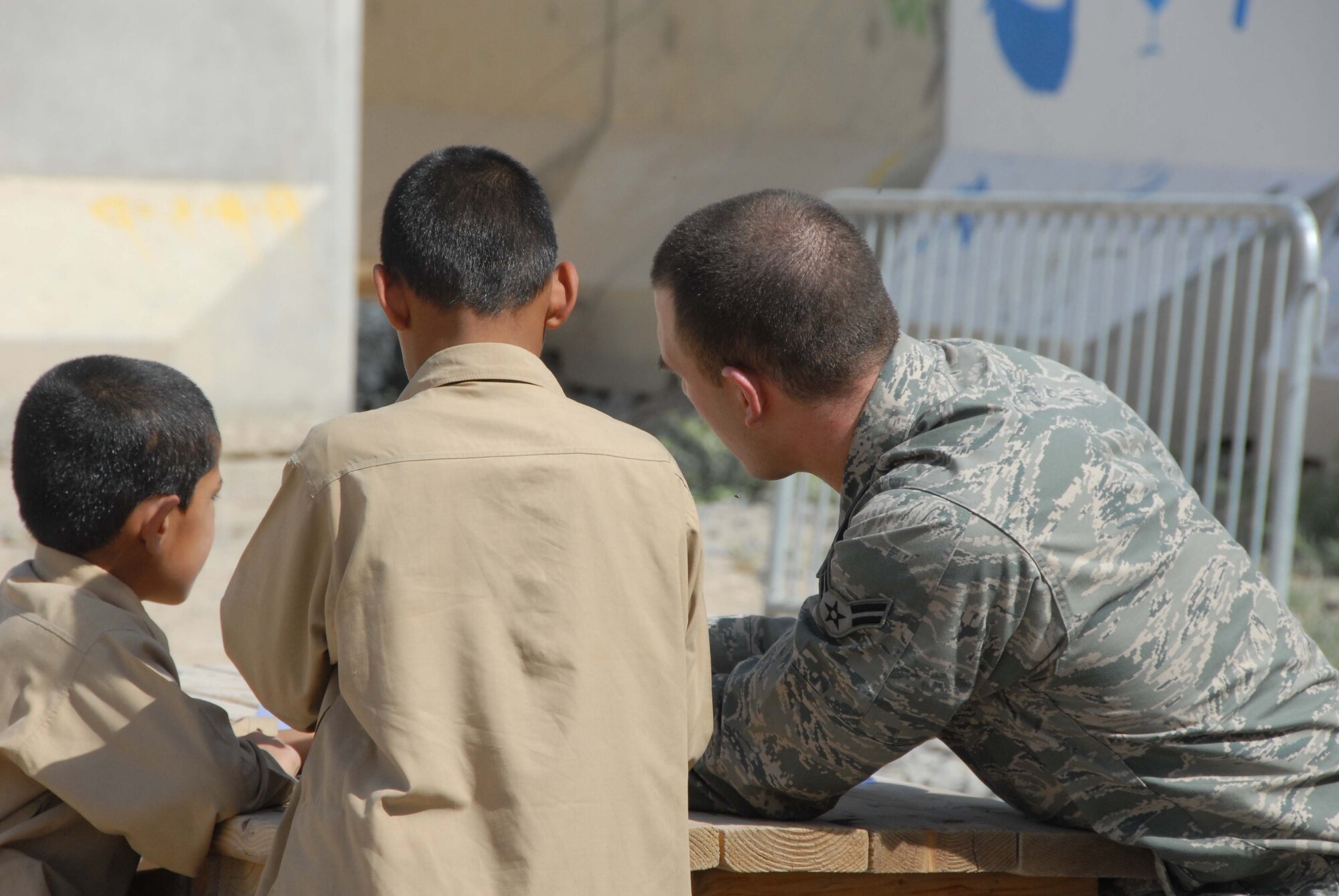 Airman First Class Garrett Lee shows Afghan boys how to fold a paper airplane at a school at Kandahar Airfield April 30, 2011. Airman Lee was part of a group that volunteered to participate in activities for the day, such as building the paper airplanes and playing soccer. Airman Lee works out of the 451st AEW Command Post at the airfield. (Photo by Tech. Sgt. Emily F. Alley)