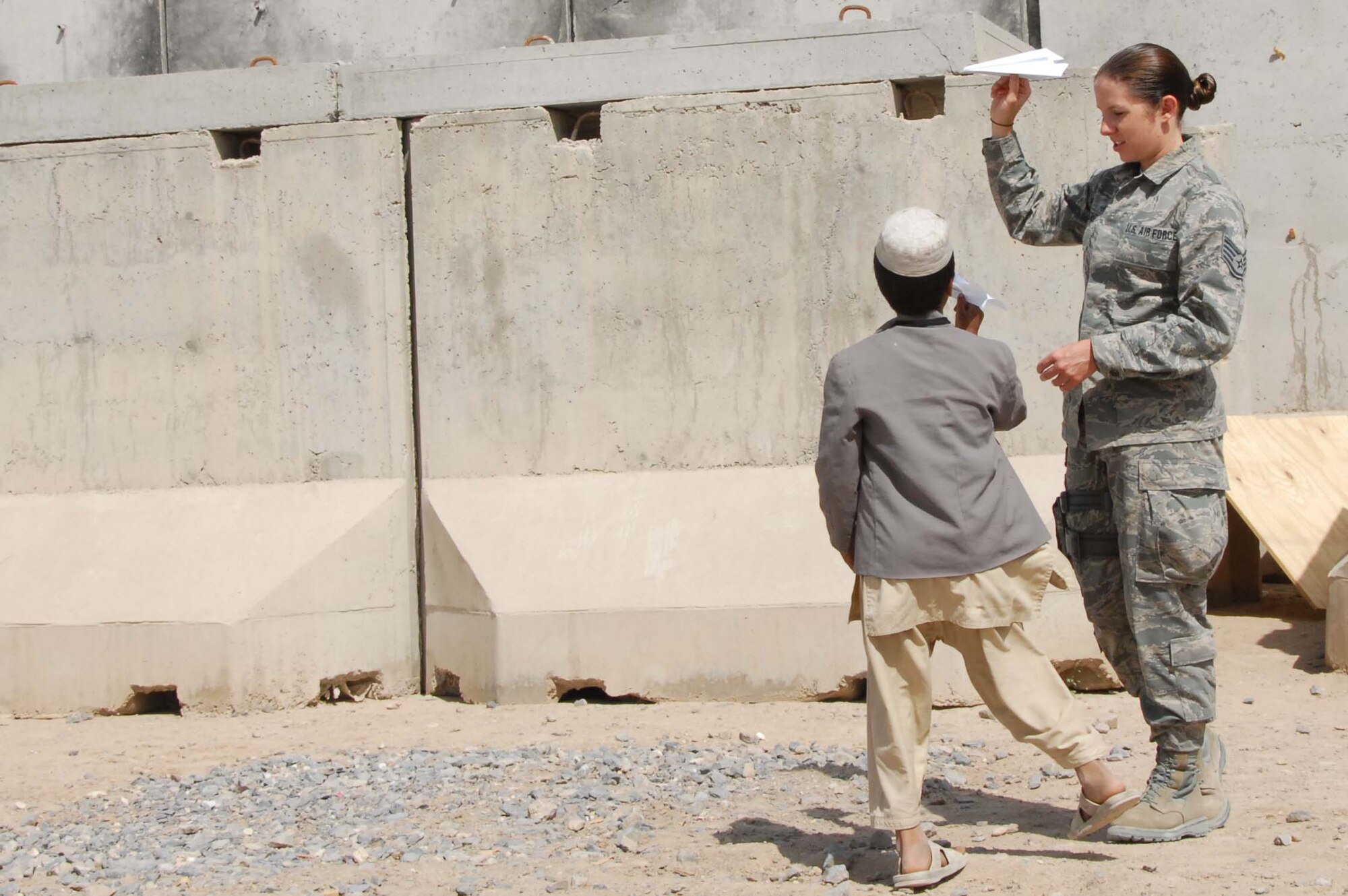 Staff Sergeant Amanda Menlove prepares to show an Afghan boy how to throw a paper airplane at a school at Kandahar Airfield, Afghanistan on April 30, 2011. She is part of a group of Airmen who volunteered to participate in activities at the school for the day that included building the paper airplanes and playing soccer. Sergeant Menlove works out of the 451st AEW command post at Kandahar Airfield. (Photo by Tech. Sgt. Emily F. Alley)