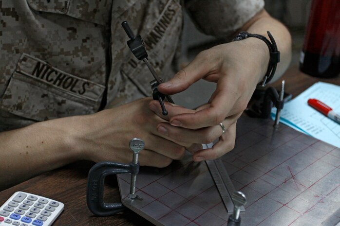 A Marine adjusts his flat leg divider to accurately measure the distance between two holes he plans on drilling into a metal plate he was given during a Hole Quality Course at the Marine Aviation Logistics Squadron 12 Airframes’ warehouse here May 4. During the course, the Marines learned the process involved in properly lubricating their drill bits and how to drill at a true 90-degree angle into aluminum, titanium and steel.