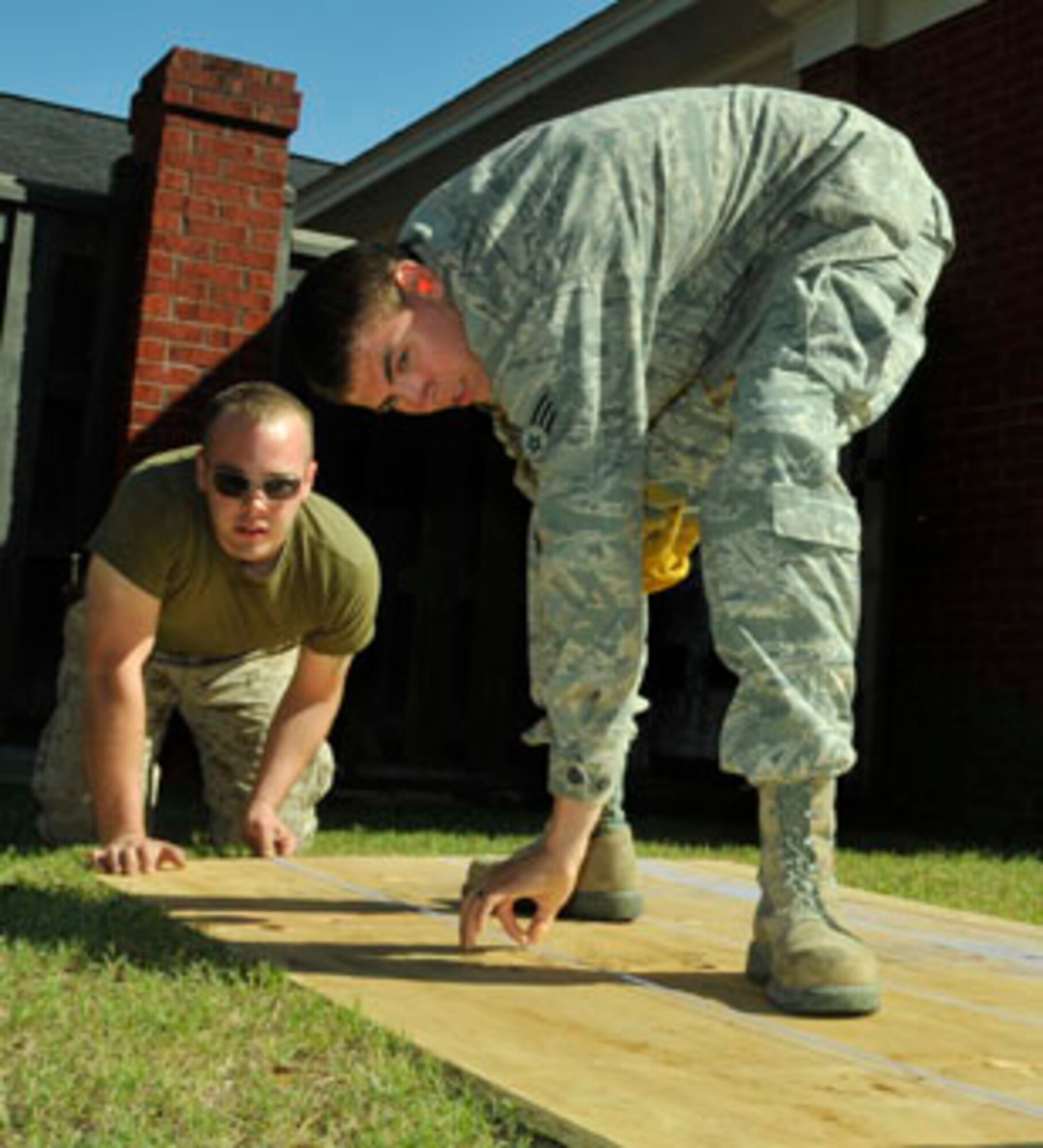 Senior Airman Joshua Frye, a structural specialist from the 176th Civil Engineer Squadron, and Marine Cpl. Benjamin Greenwald, from the 6th Engineer Support Batallion, prepare plywood for cutting May 5 to build a patio covering at a clinic here.  Members from the 176th Wing were in Alabama for an Innovative Readiness Training (IRT) mission. The IRT program allows for real-world training opportunities for military personnel while providing needed services to under-served communities in the United States. Alaska Air National Guard photo by Staff Sgt. N. Alicia Goldberger.