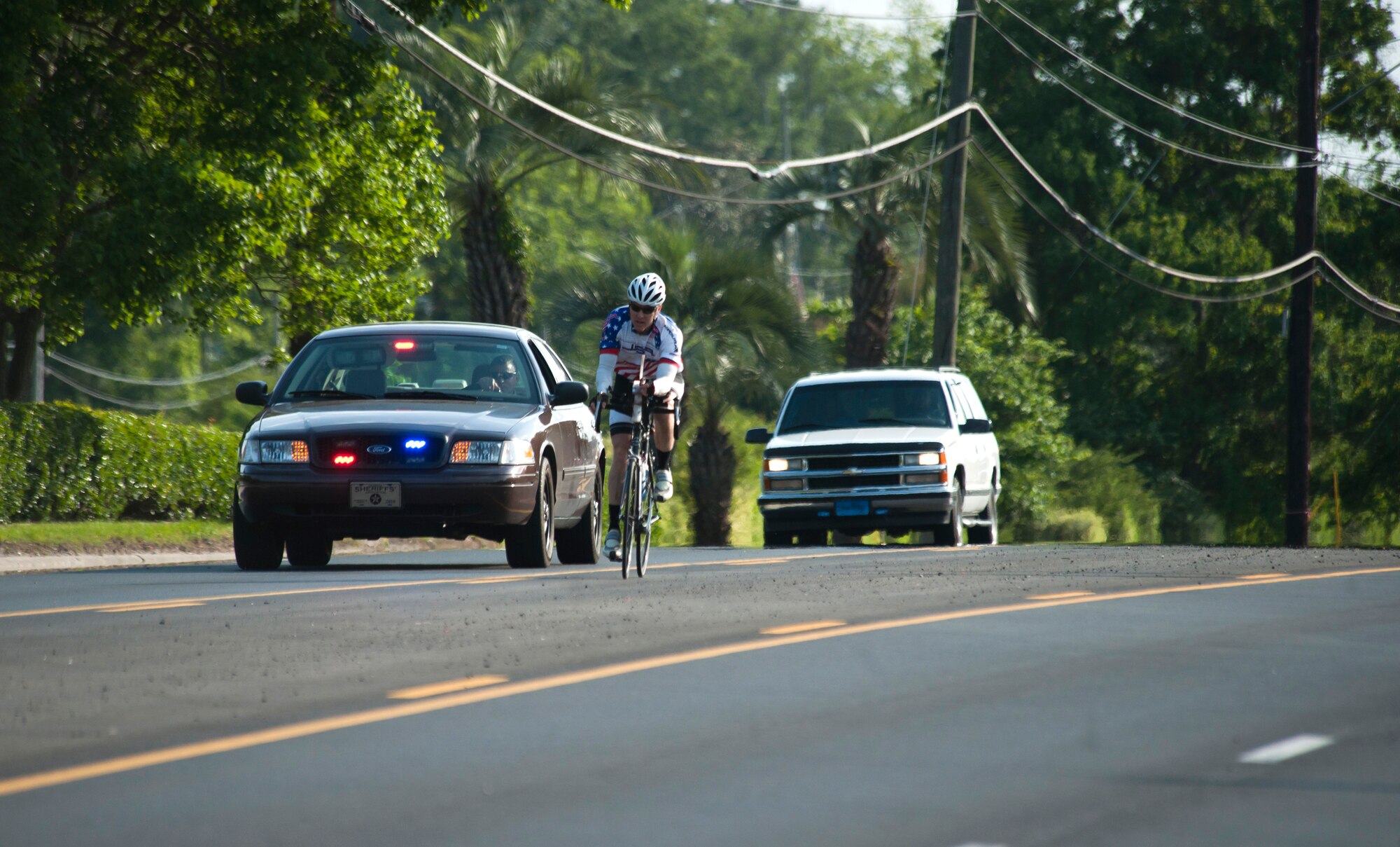 WAYCROSS, Ga. -- Jason Rogers, Air Force veteran, rides his bicycle in Waycross, Ga., May 2 on the final stretch of his journey to meet a crowd full of friends and family. Mr. Rogers had two police car escorts to lead him to the finish. (U.S. Air Force photo/Airman 1st Class Jarrod Grammel)(RELEASED)