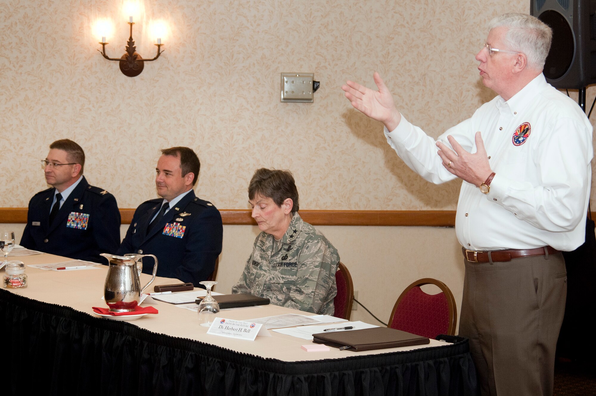 Dr. Herbert Bell (standing), technical advisor for the 711th Human Performance Wing, Human Effective Directorate’s Warfighter Readiness Research Division (711 HPW/RHA) in Mesa Ariz., greets participants at the division’s symposium. Speakers included (seated) Colonel Douglas Hodge, deputy director, Human Effective Directorate, Lieutenant Colonel Joel Boswell, division chief, Warfighter Readiness Research Division, and Major General Ellen Pawlikowski, commander, Air Force Research Laboratory. (U.S. Air Force Photo by Bruce Liddil)