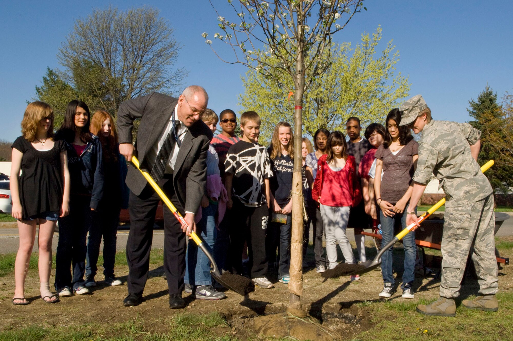 HANSCOM AIR FORCE BASE, Mass. - Col. Stacy Yike (right), 66th Air Base Group commander,  and Tom Schluckebier (left), Hanscom's base civil engineer, shovel dirt into a new pear tree planted April 29 across from the clinic as students from Hanscom Middle School watch. The tree was planted to celebrate Arbor Day. (U.S. Air Force photo by Mark Wyatt)