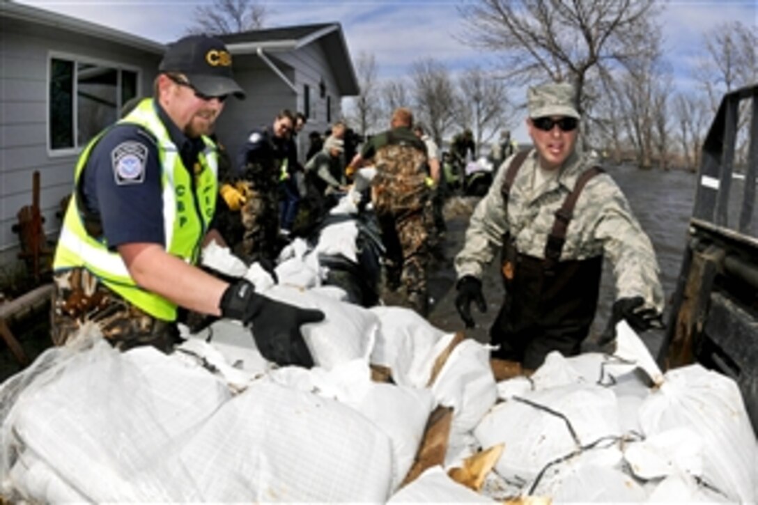 U.S. Air Force Tech. Sgt. Tracy Winterquist (right) and Ryan Latozke (left) unload sandbags to create a barrier blocking rising overland flood water around a house in Cass County, N.D., on April 29, 2011.  Winterquist, assigned to the 119th Civil Engineer Squadron, is a member of a North Dakota National Guard quick response force.  Latozke works for U.S. Customs and Border Protection.  