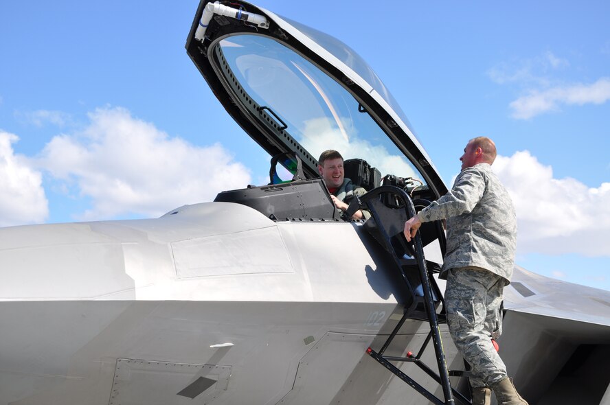 JOINT BASE ELMENDORF-RICHARDSON Alaska--Master Sgt. Ernie Kunde climbs the ladder to greet F-22 pilot Maj. Kevin Sutterfield upon his return from Alaska's Aviation Trade Show held this past weekend at the Ted Stevens Airport.  Members of the Air Force Reserve's 477th Fighter Group took the jet to be a part of the show that included more than 275 vendors and was attended by more than 21,000 visitors. (Air Force Photo/Maj. Lisa Reaver)